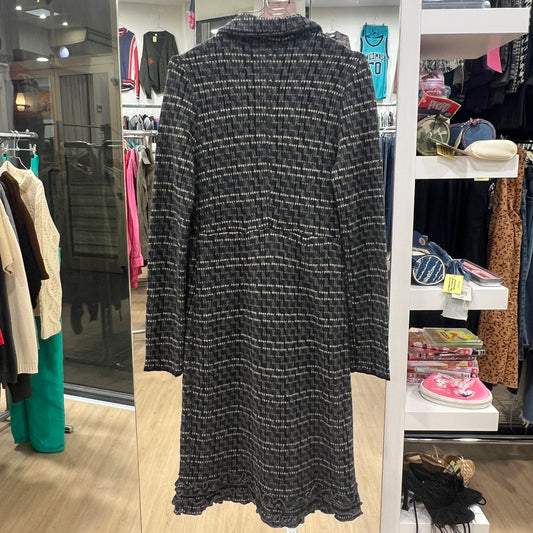 Black patterned dress in a store setting with shelves and other clothing in the background