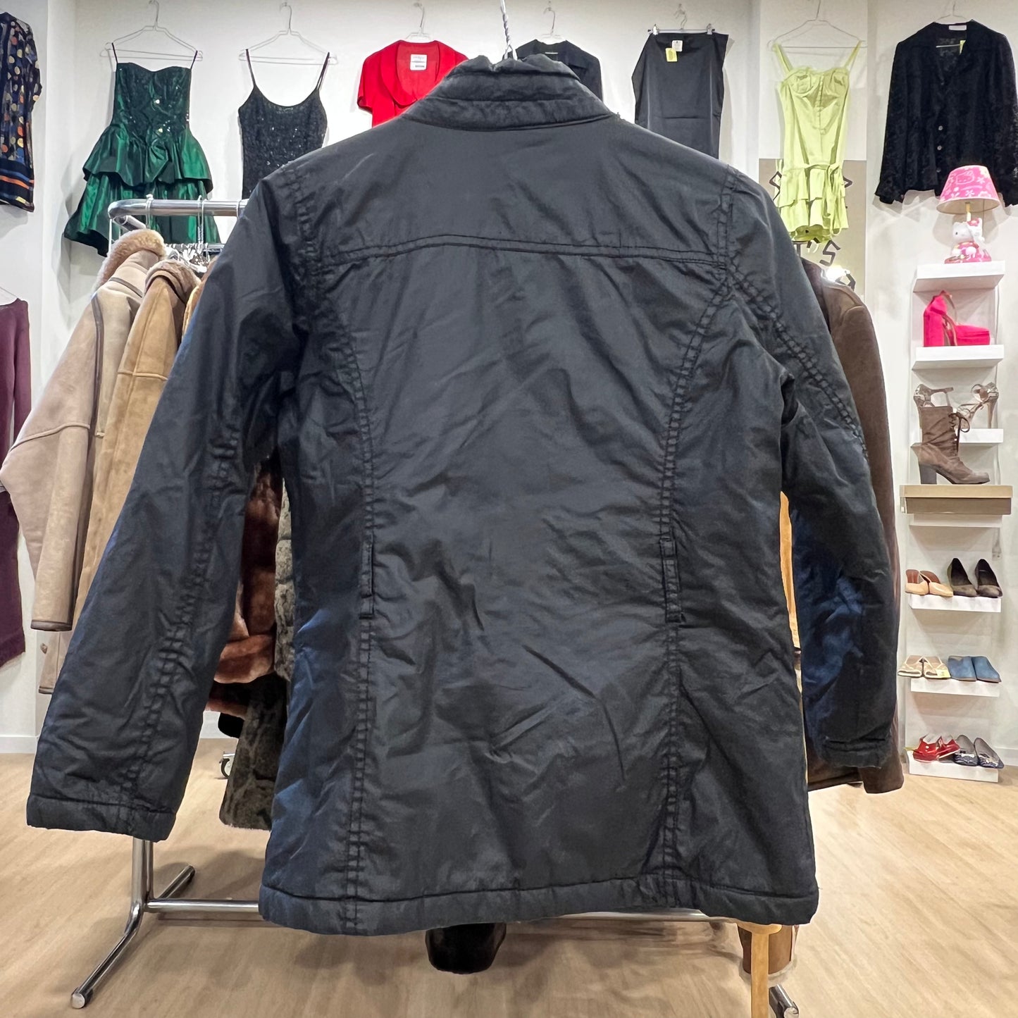 Black jacket on a mannequin in a clothing store with various garments in the background