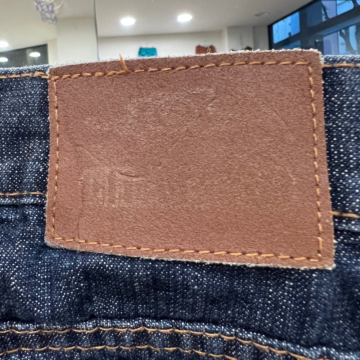 Close-up of a leather label on denim fabric with a blurred indoor background