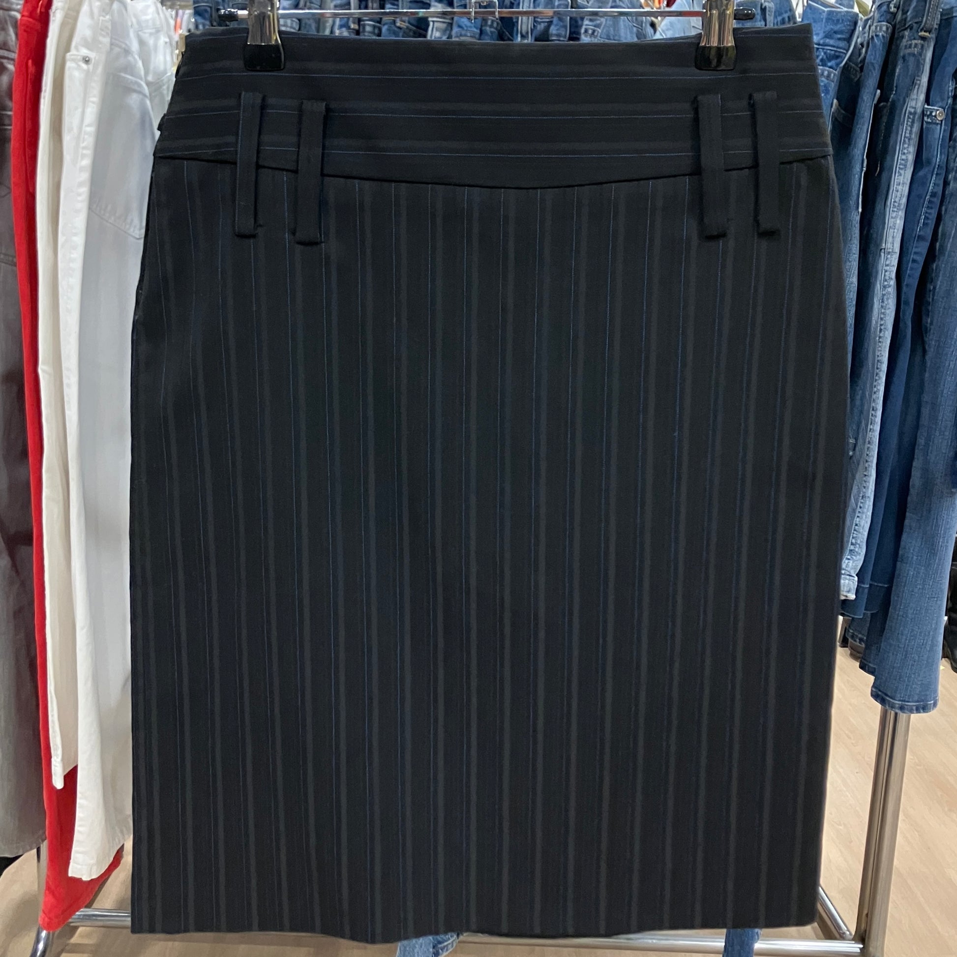 Black pinstripe skirt hanging on a rack with other clothing items
