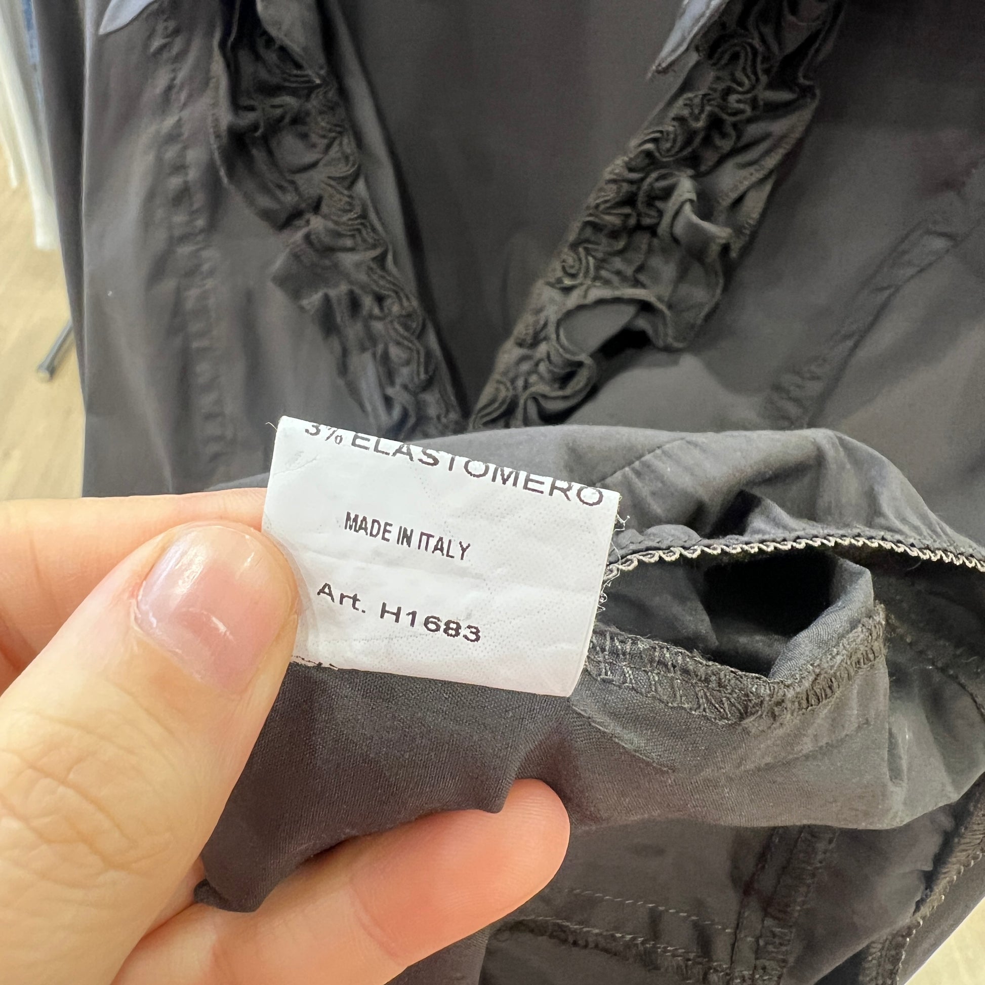Gray jacket with a visible label held by a hand