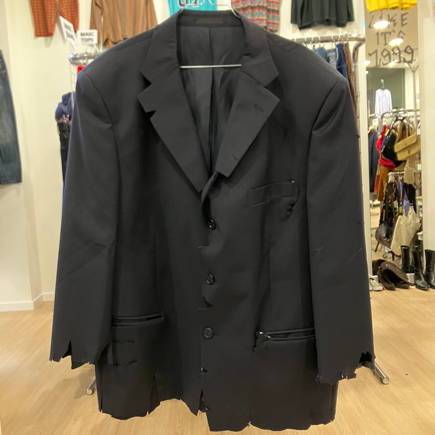 Black blazer on a hanger in a store setting