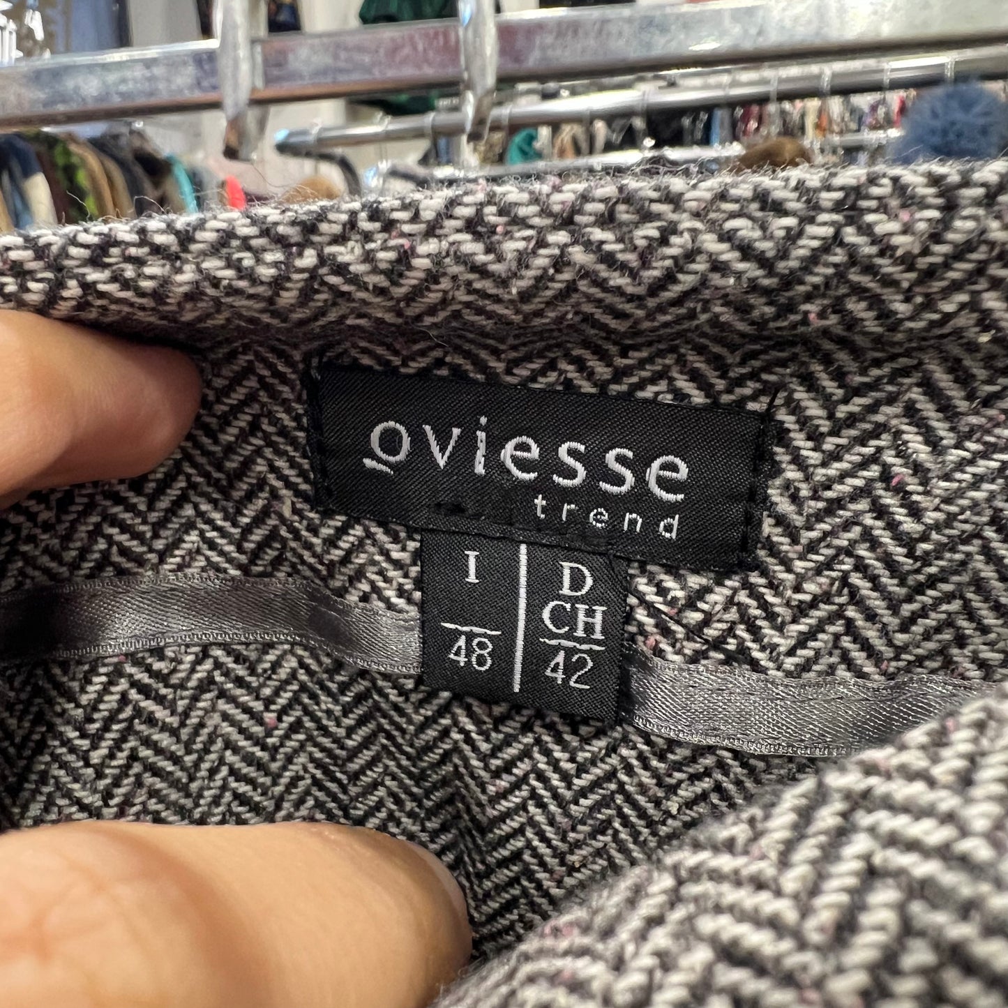 Close-up of a patterned fabric with 'oviesse' label on a clothing rack background