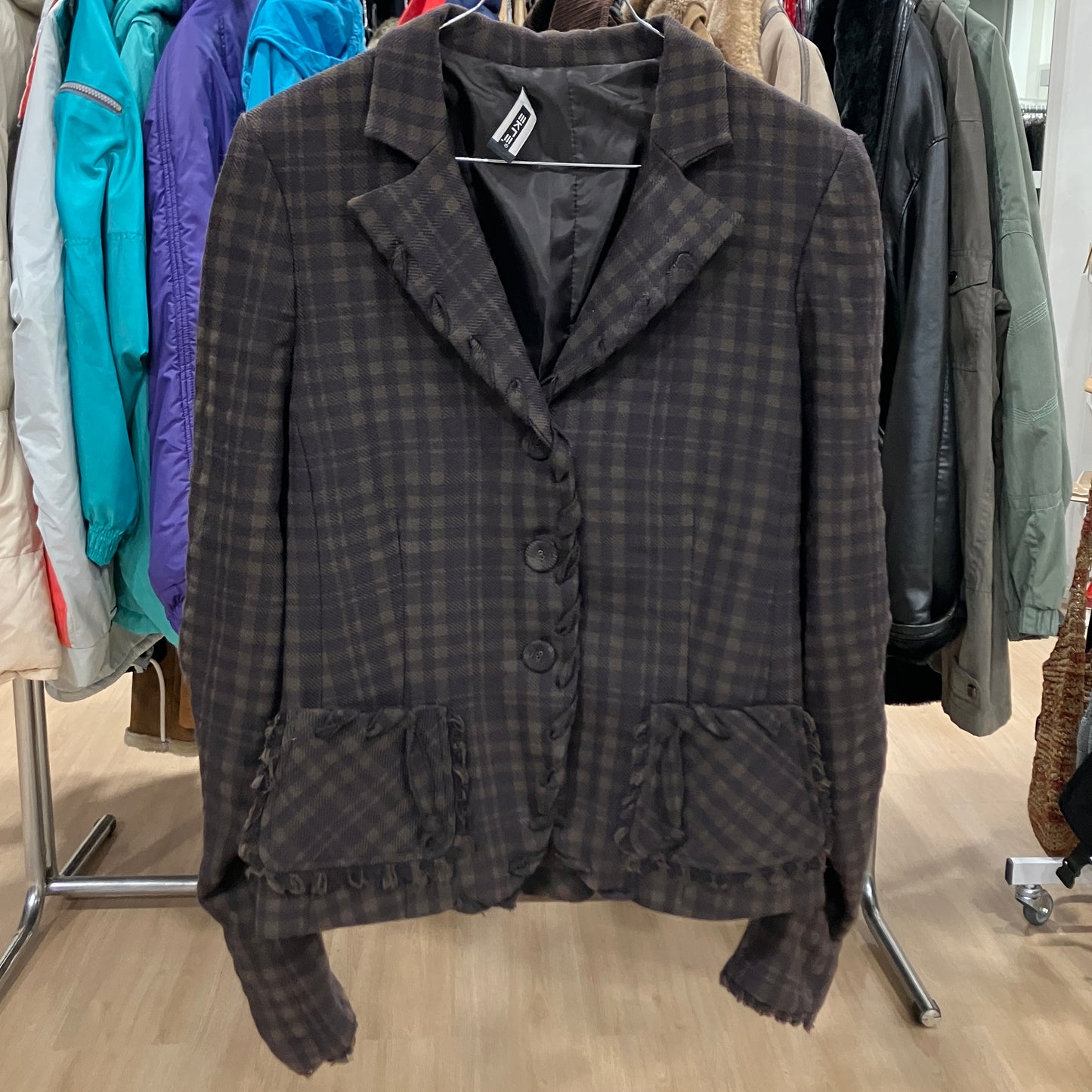 Plaid jacket hanging on a rack with other clothing in the background