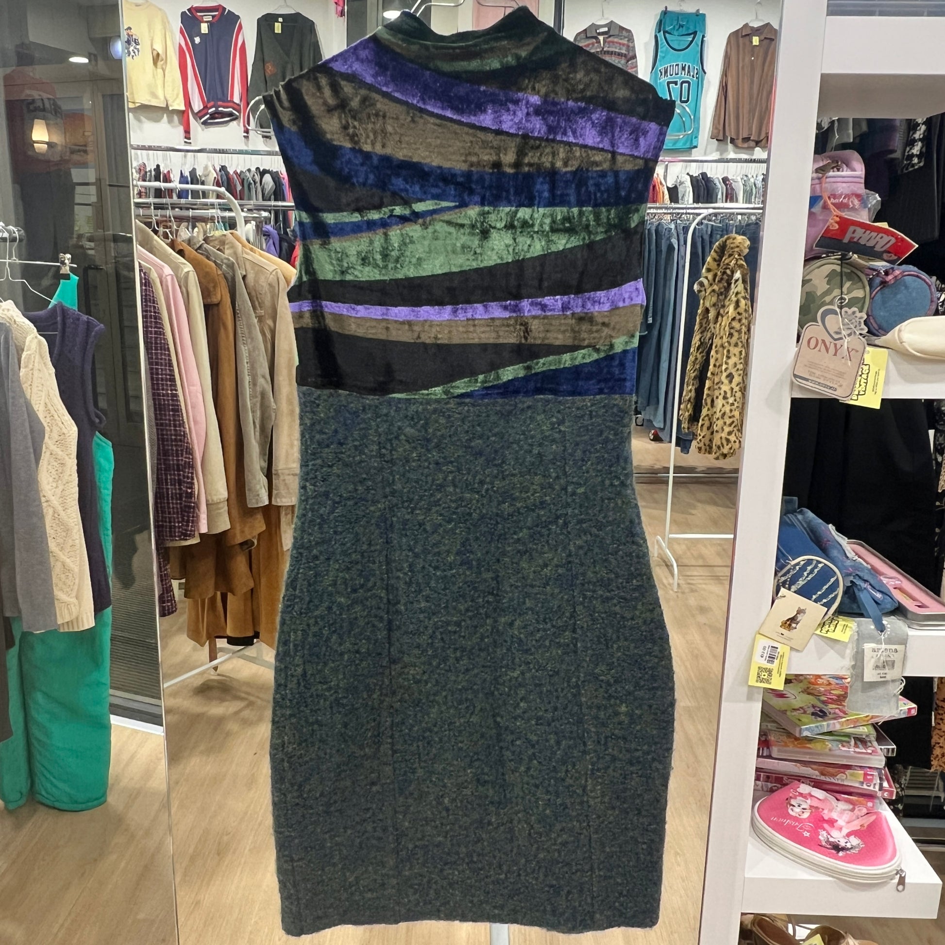 Multicolored striped dress in a store setting with racks of clothes in the background
