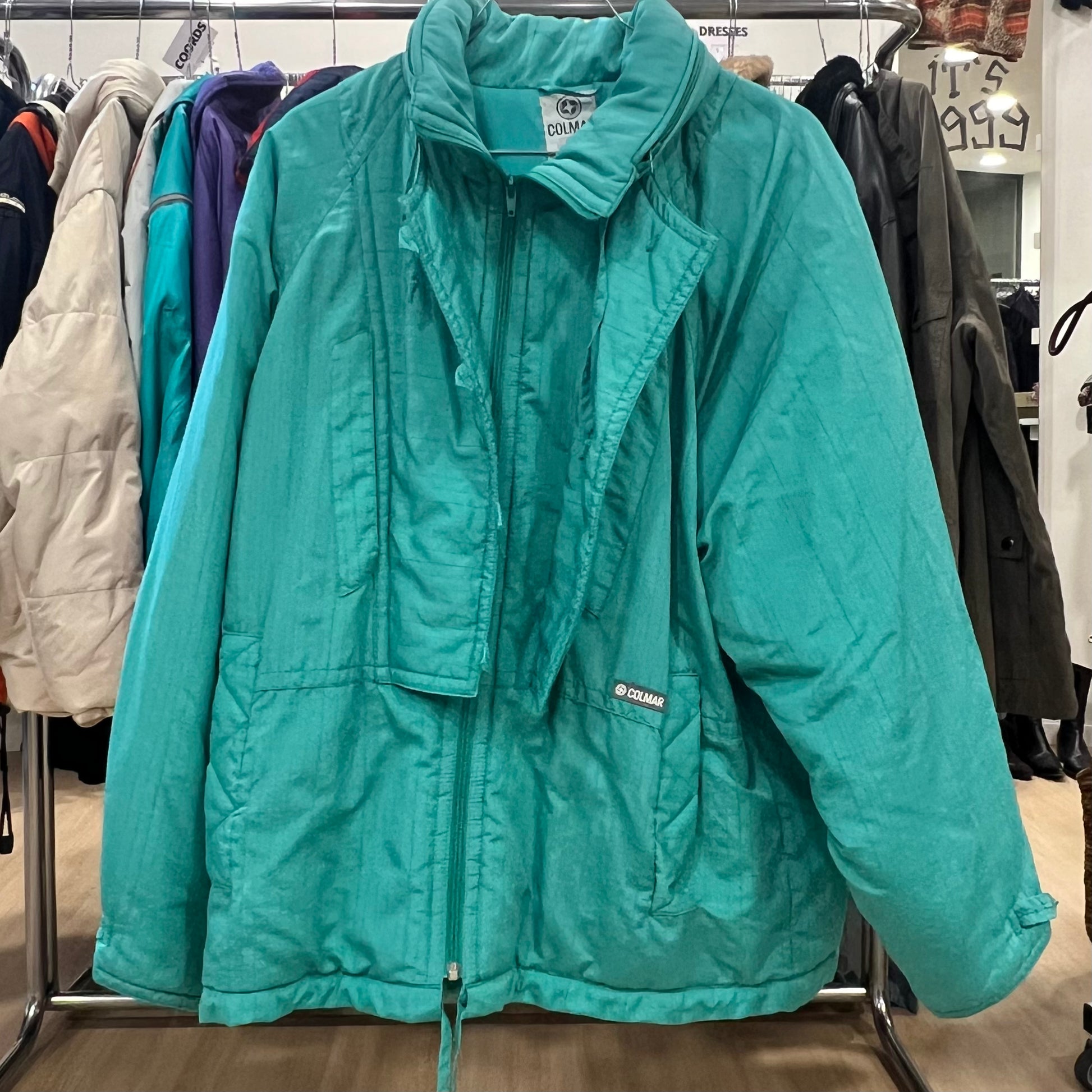 Teal jacket on a rack in a store setting