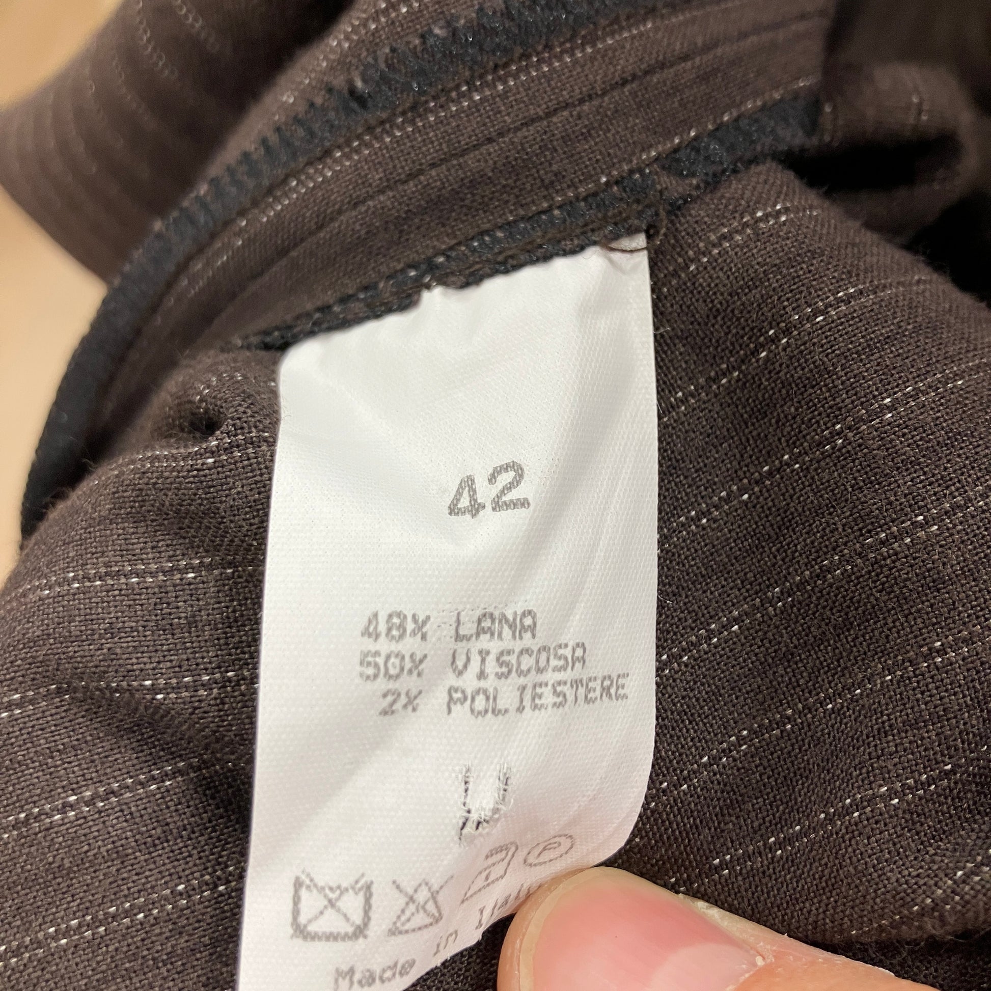 Close-up of a clothing label on a brown fabric garment with visible text