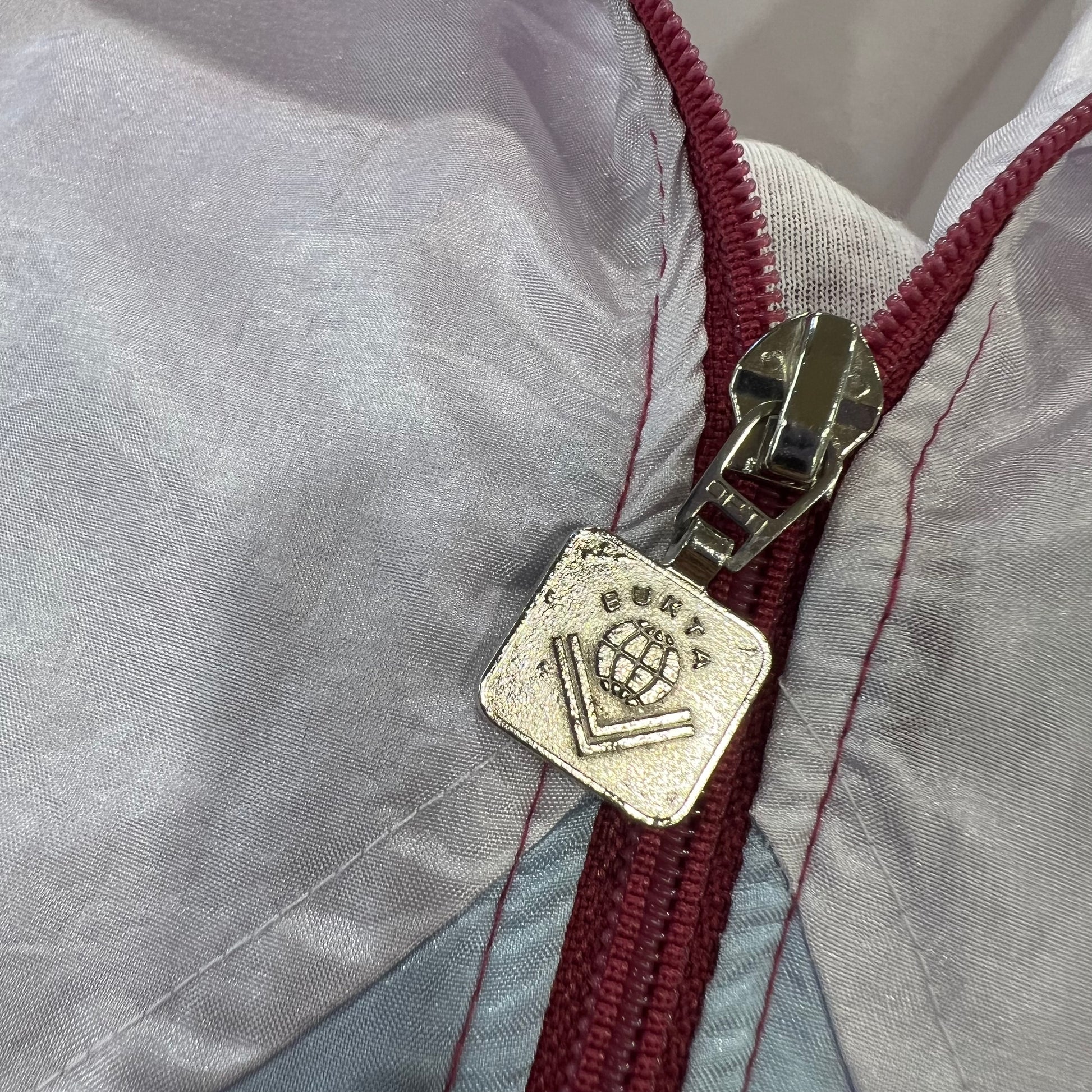 Close-up of a zipper on a gray jacket with a brand logo tag