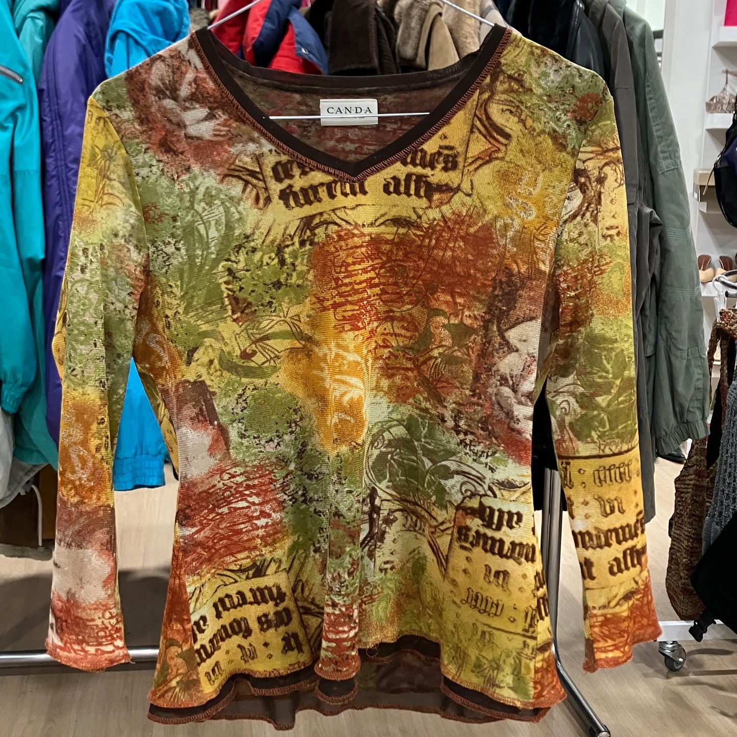 Colorful long-sleeve shirt with text and graphics on a hanger in a store setting