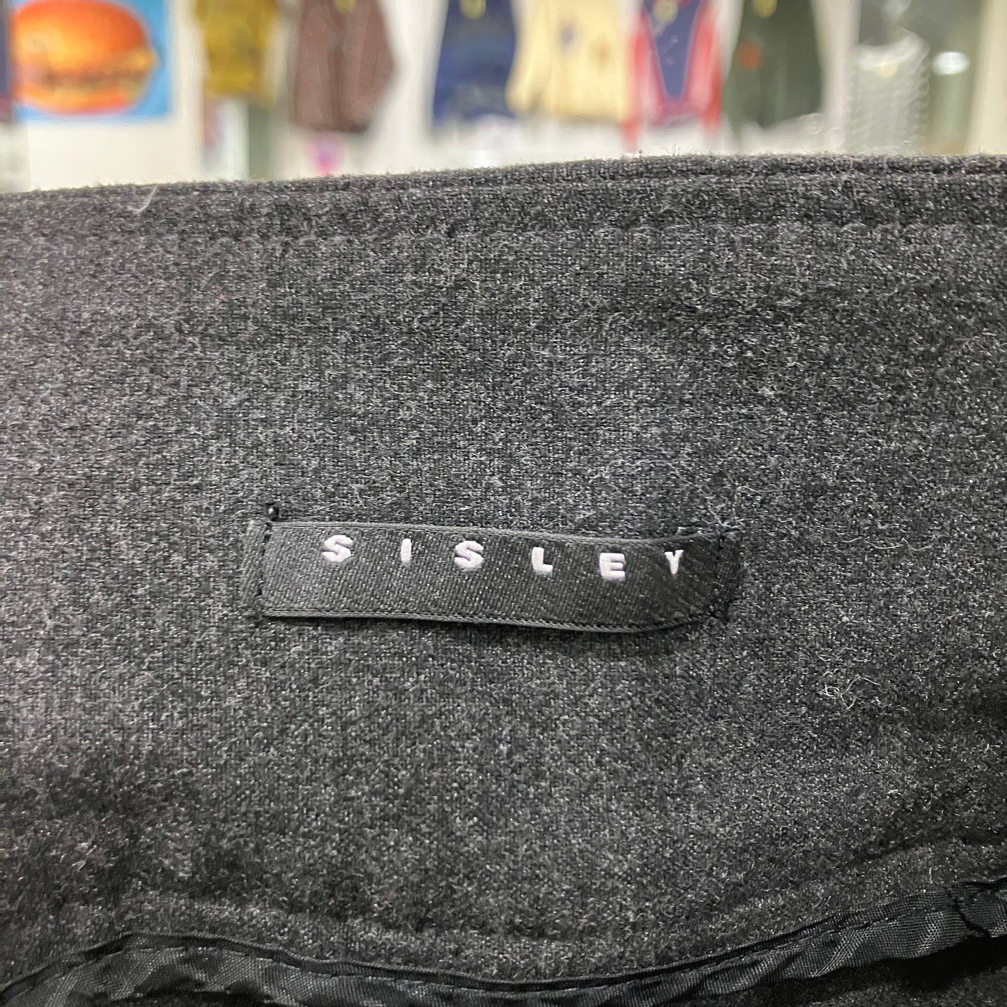 Black textured bag with 'Sisley' label in a store setting