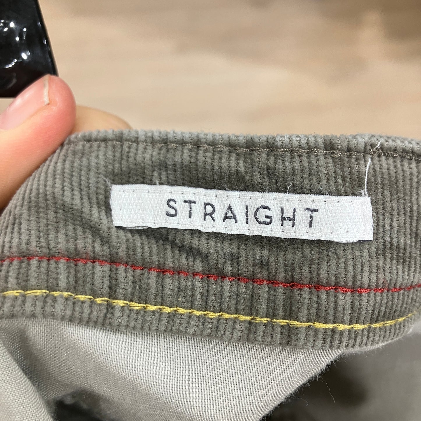 Gray fabric with a 'STRAIGHT' label held by a hand