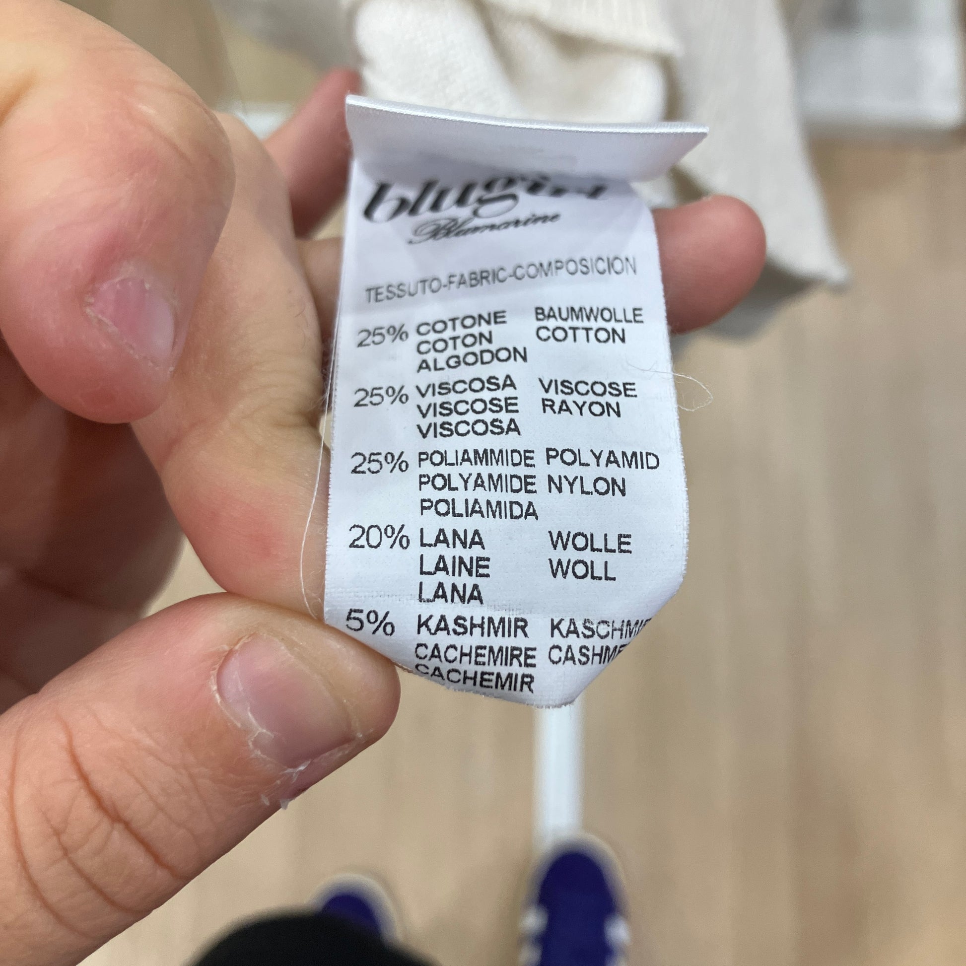 Close-up of a fabric composition label held by a hand