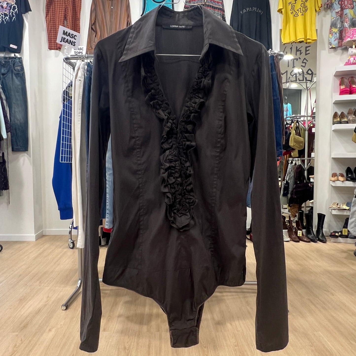 Black ruffled shirt on a hanger in a clothing store