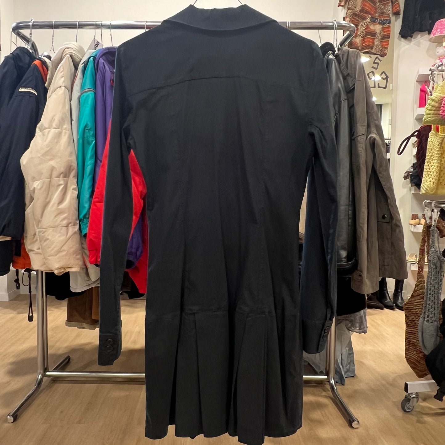 Black long-sleeve dress with a collared neckline hanging on a rack in a clothing store