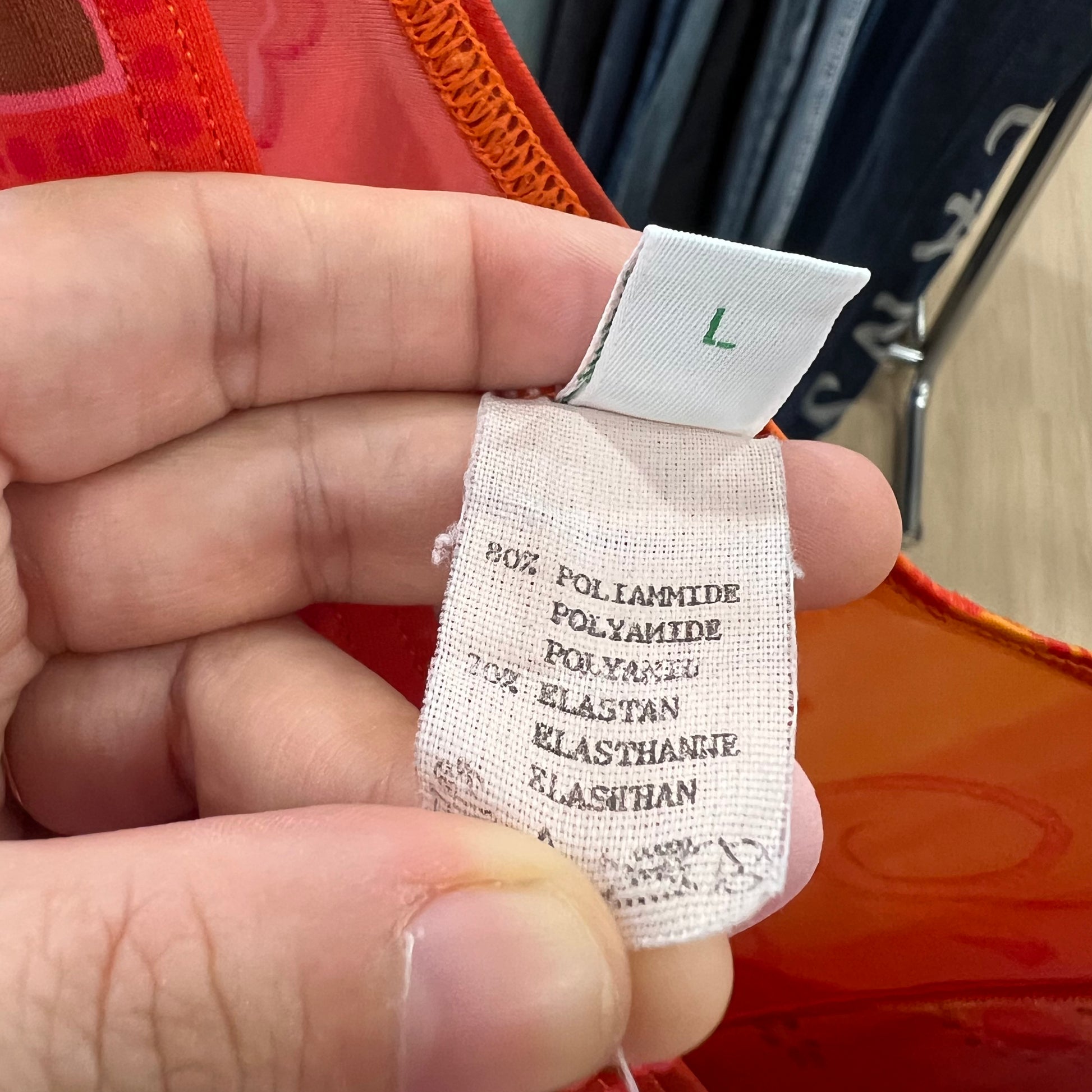 Clothing label held between fingers with a blurred background