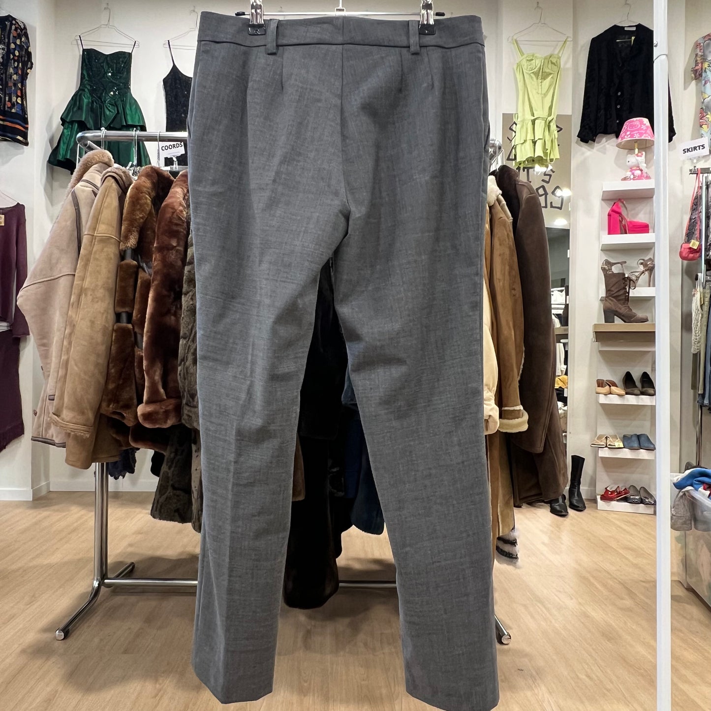 Gray pants hanging in a clothing store with various garments in the background