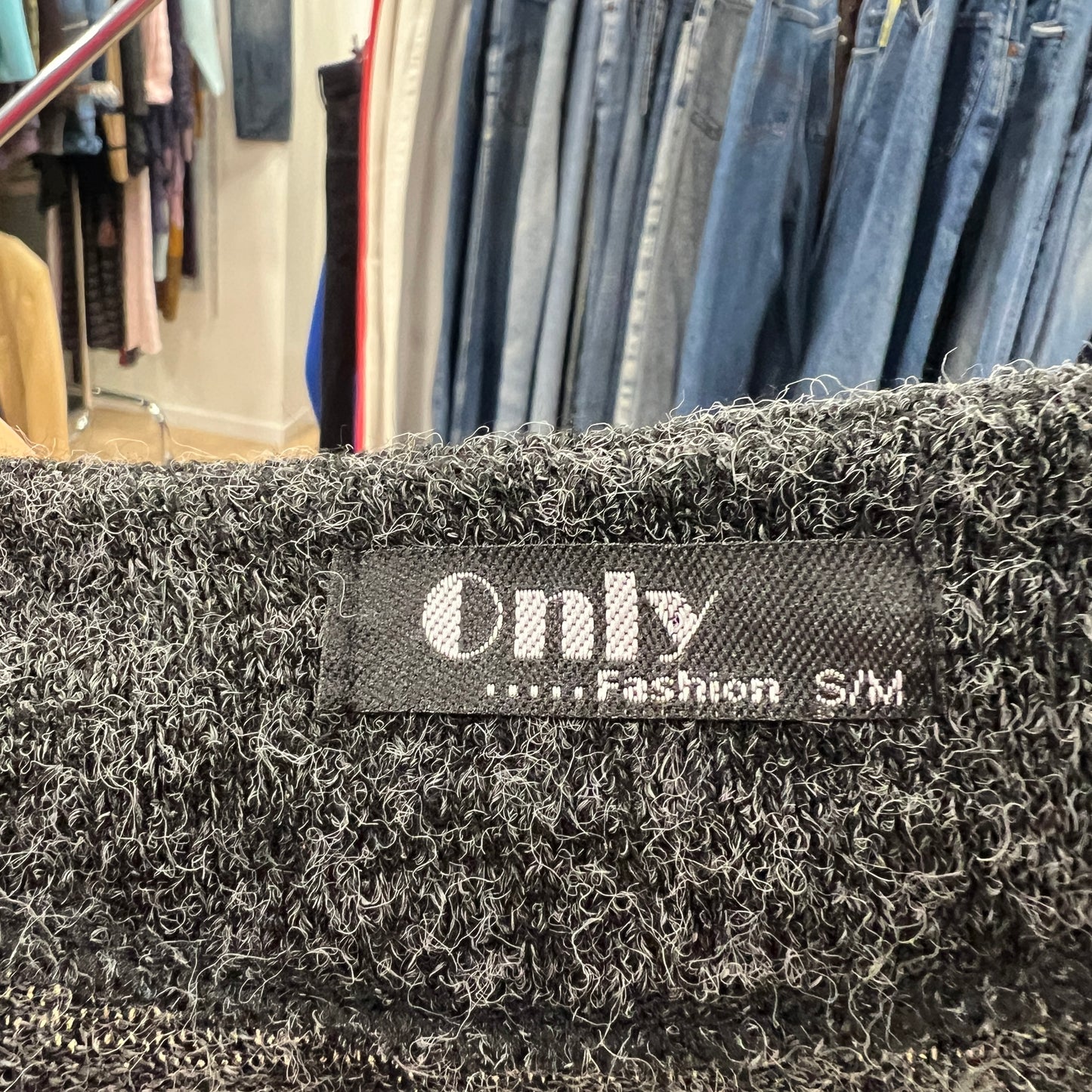 Close-up of a 'Only' brand label on a textured fabric with clothing in the background