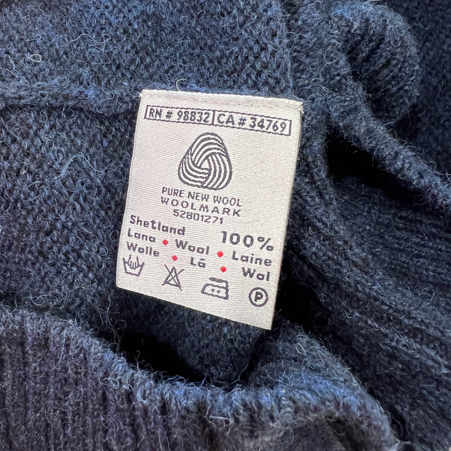 Label on a blue knitted fabric indicating 'Pure New Wool' and 'Woolmark'