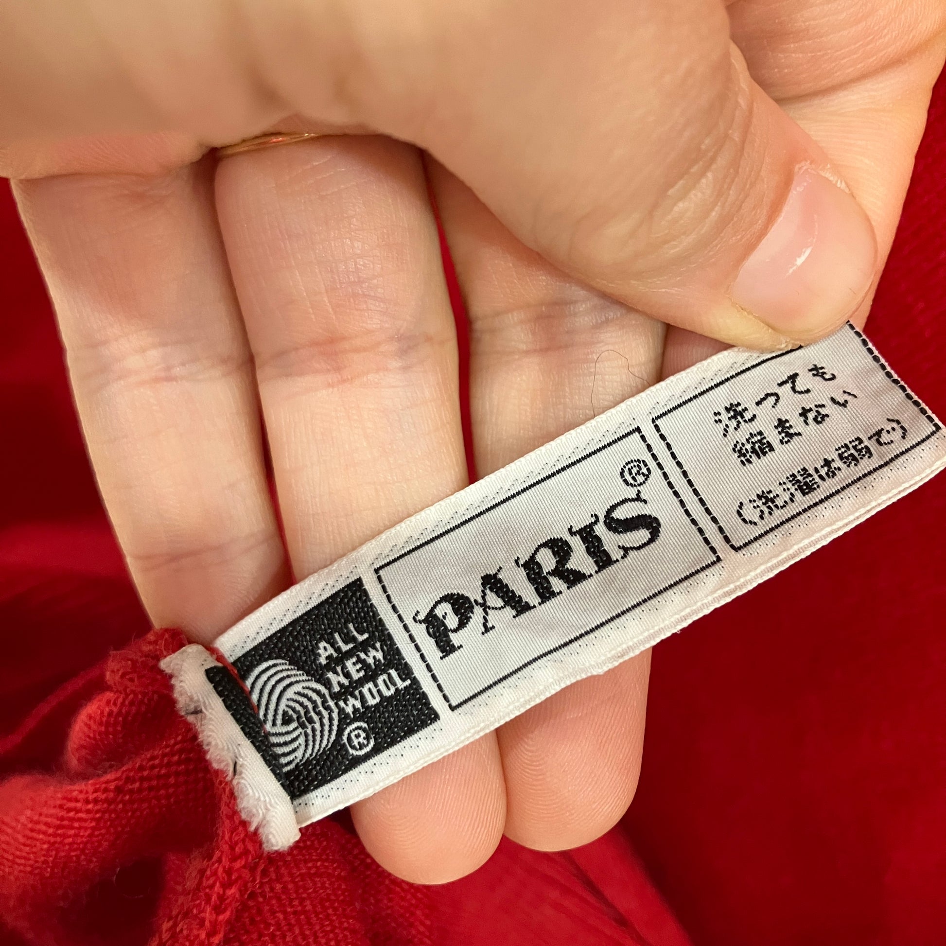 Close-up of a hand holding a clothing label with 'Paris' branding