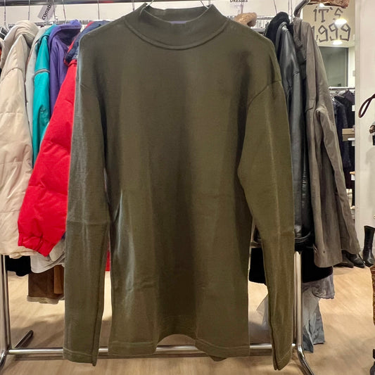 Green sweater on a rack with other clothing in the background