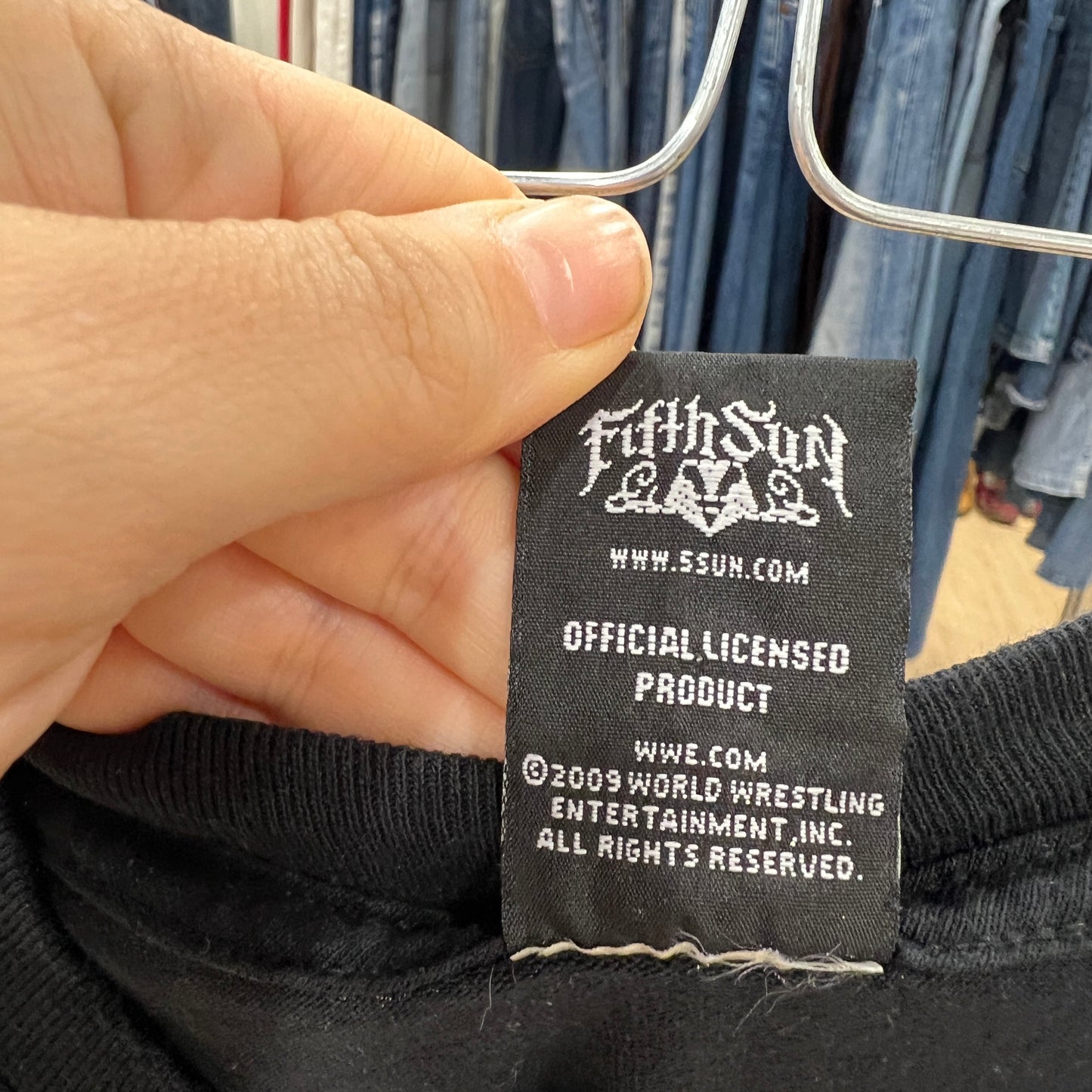 Close-up of a Fifth Sun branded tag on a product with jeans in the background