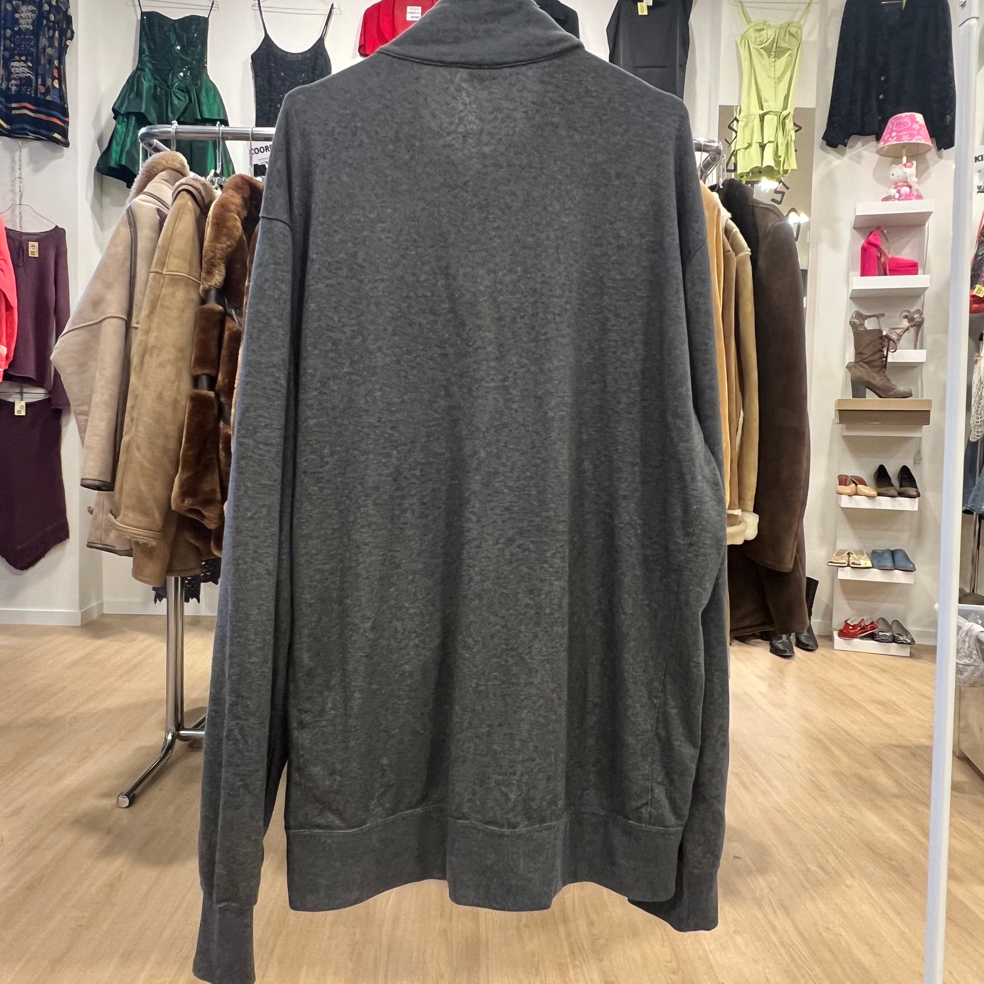 Gray track jacket on a rack in a clothing store with various garments in the background