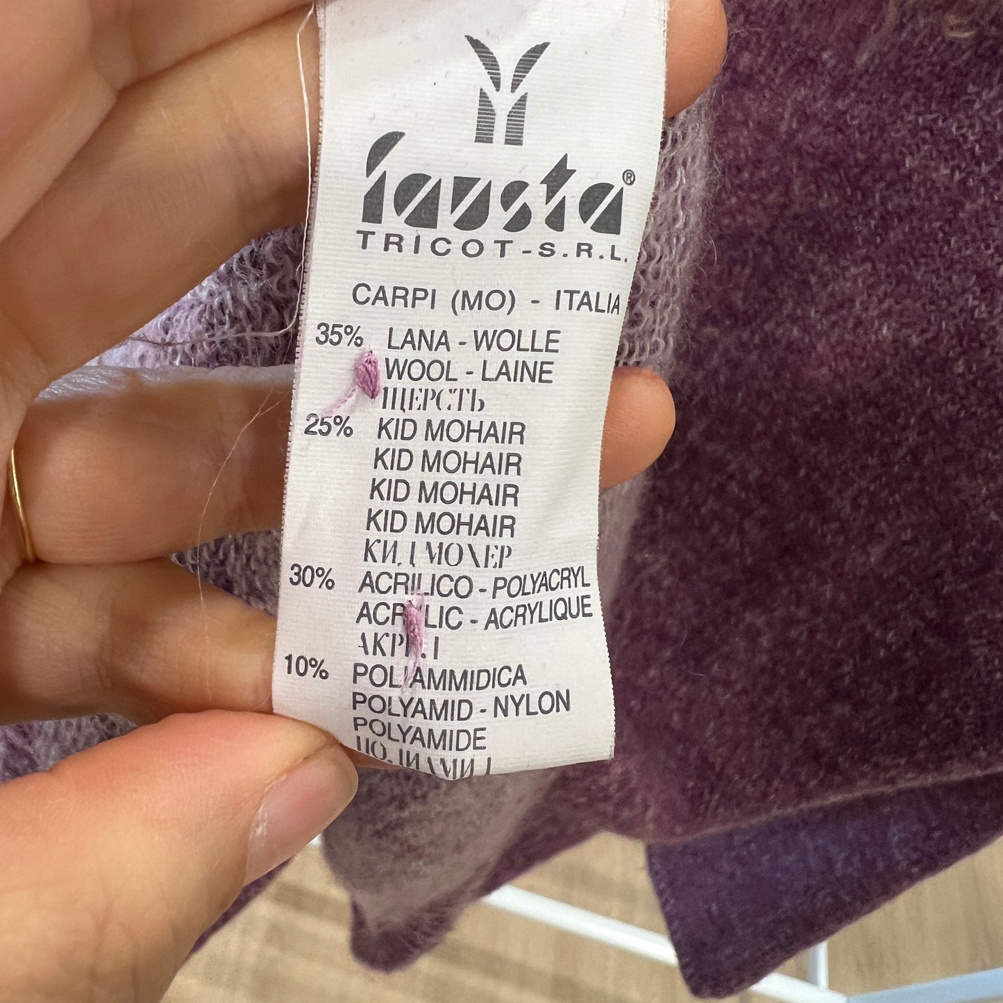 Fabric label with brand name and material composition held by a hand