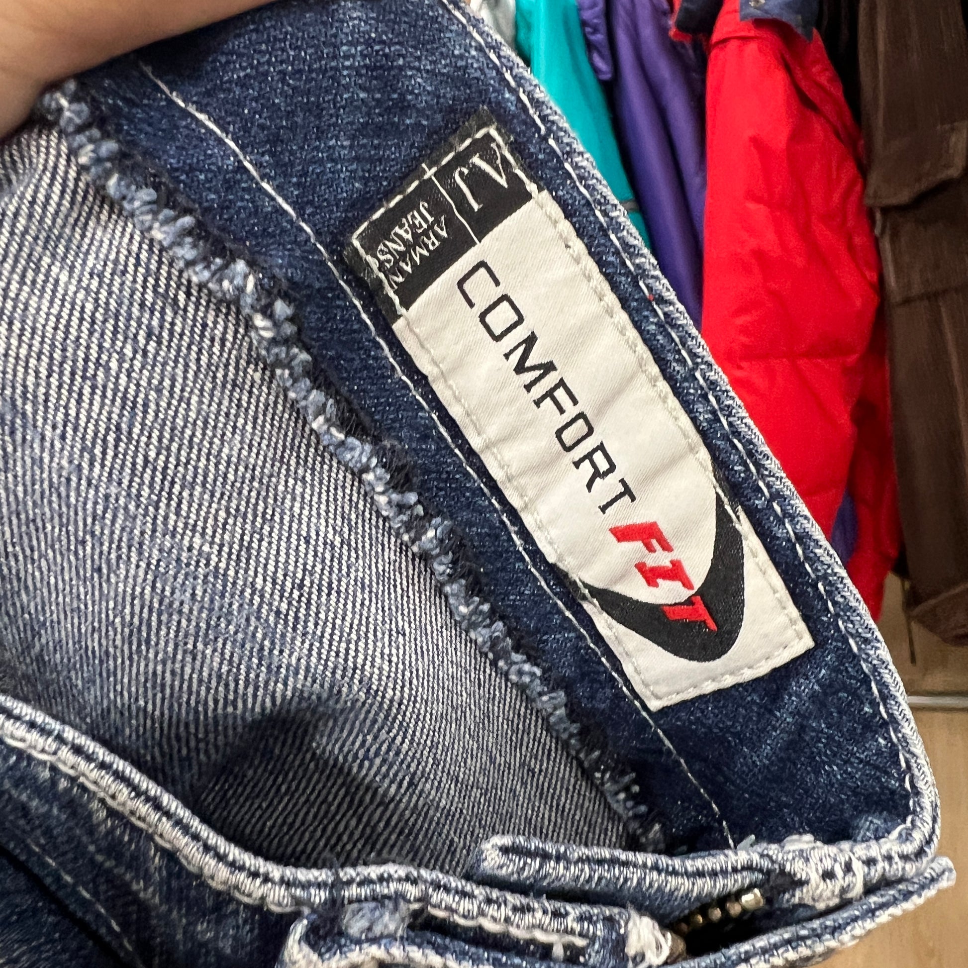 Close-up of an inner label on Armani Jeans denim pants, showing the “Comfort Fit” tag stitched along the waistband with visible blue denim texture around it
