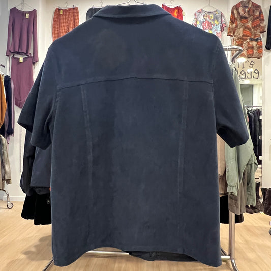 Navy blue shirt on a hanger in a clothing store with various garments in the background