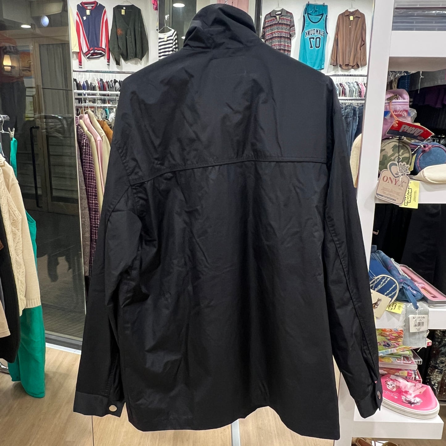 Black jacket displayed in a store with clothing racks in the background