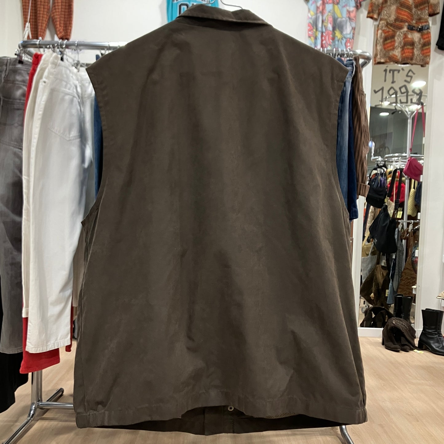 Brown vest on a rack in a clothing store with various garments in the background