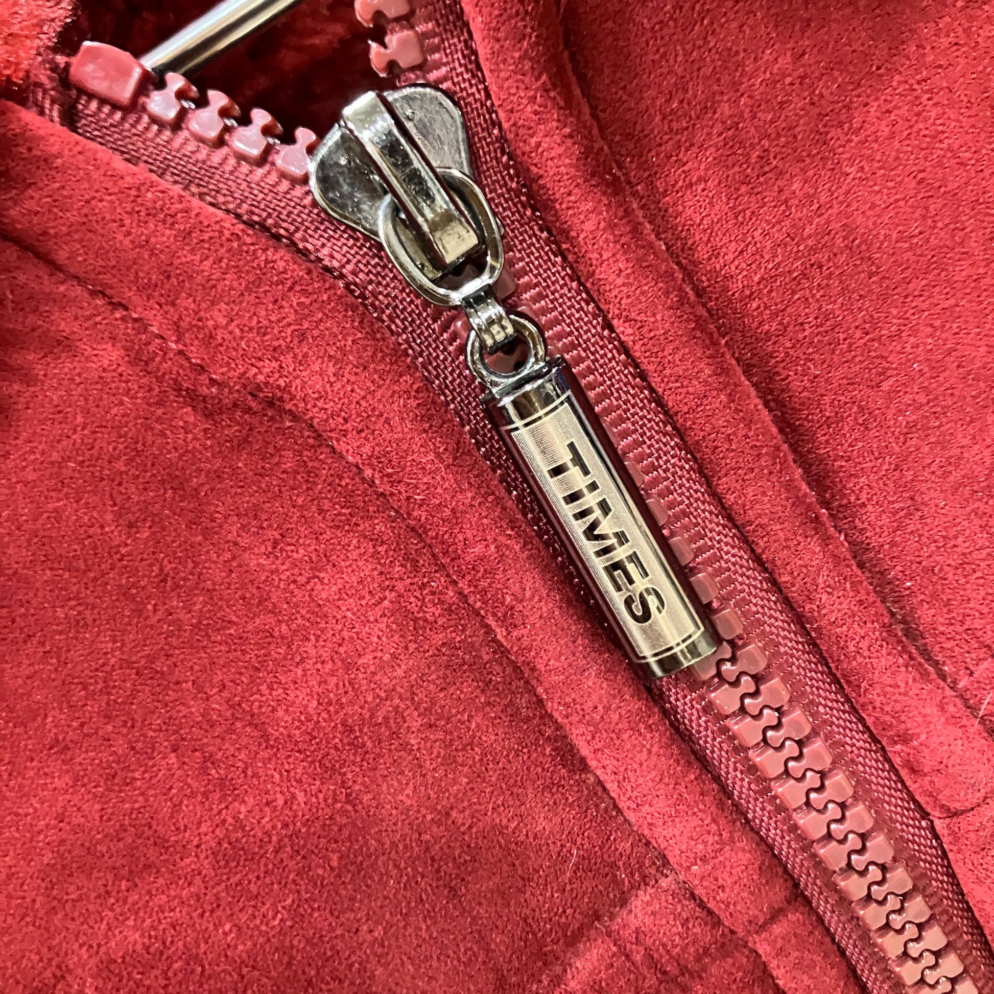 Close-up of a red zipper with a silver zipper pull featuring 'TIMES' branding