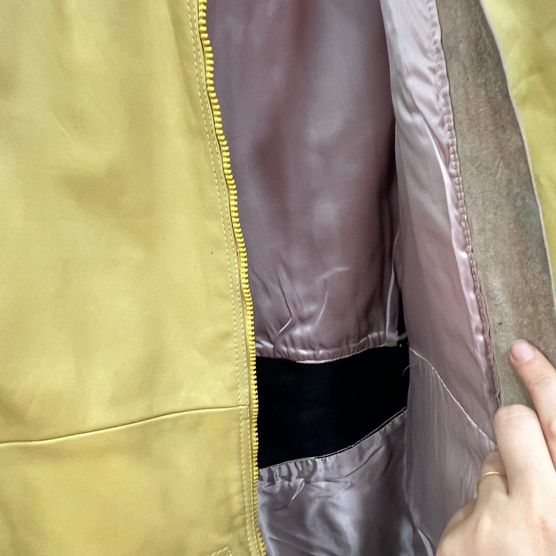 Close-up of a person opening a yellow jacket with a zipper