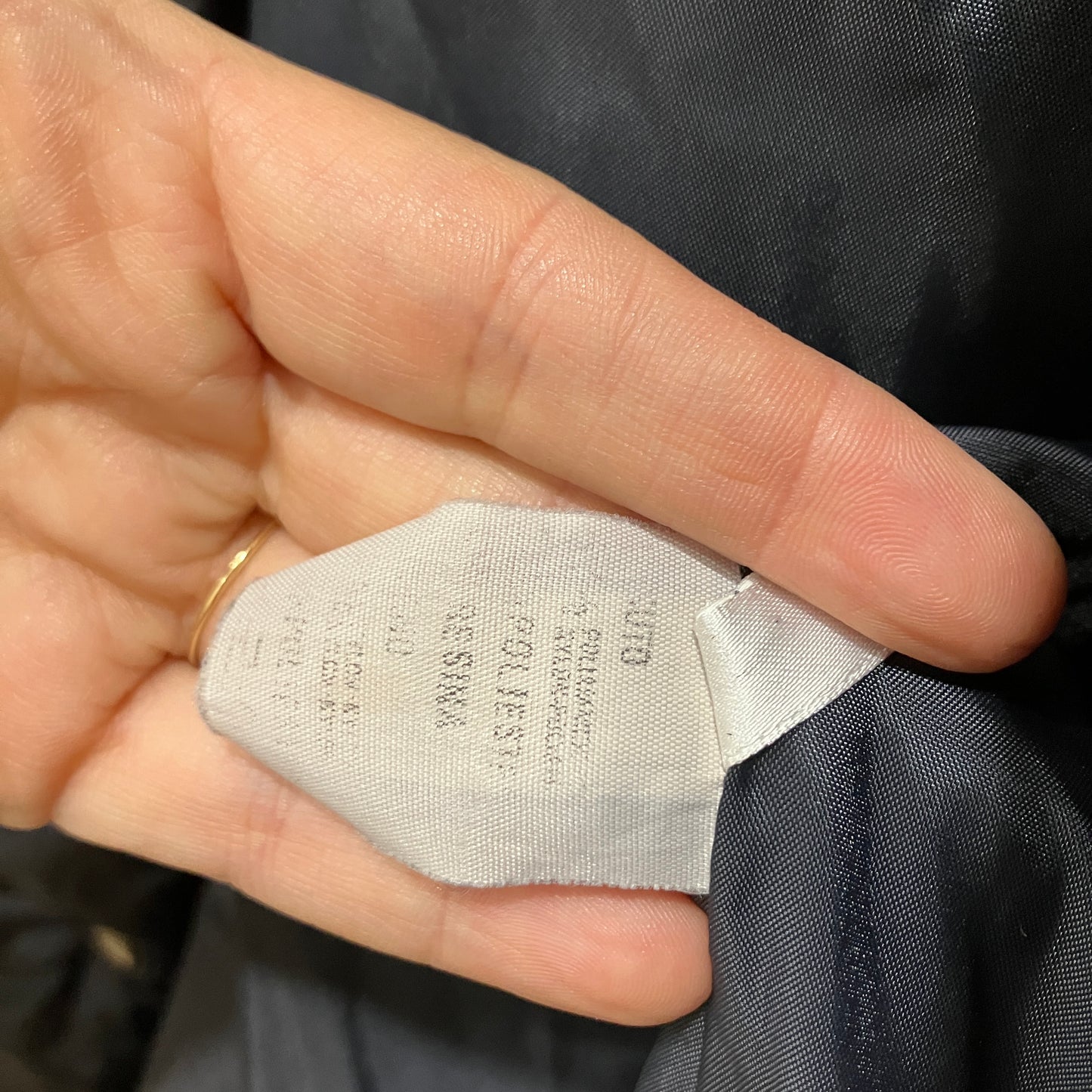 Close-up of a clothing label held by a hand with a blurred background