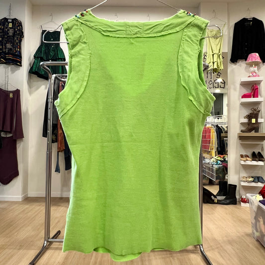 Green tank top on a rack in a store setting with various clothing items in the background.