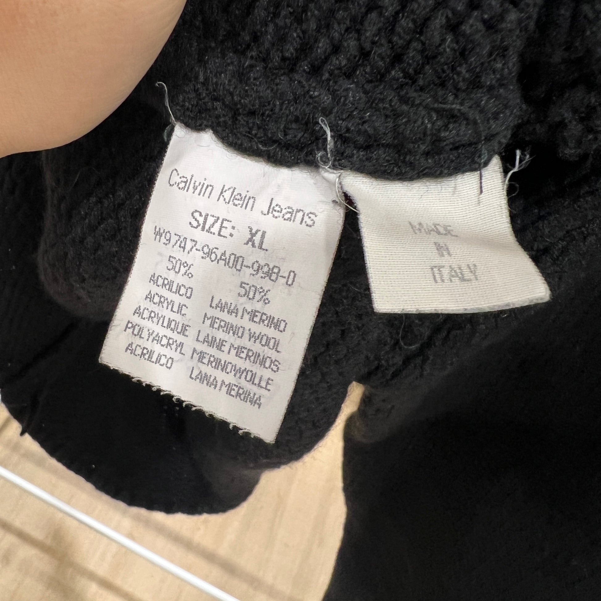 Close-up of Calvin Klein Jeans label on a black garment with beige background