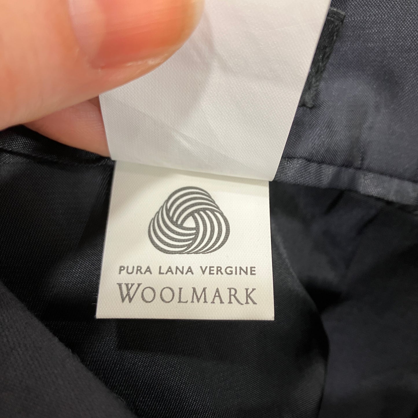 Woolmark label on a garment with a hand holding it open