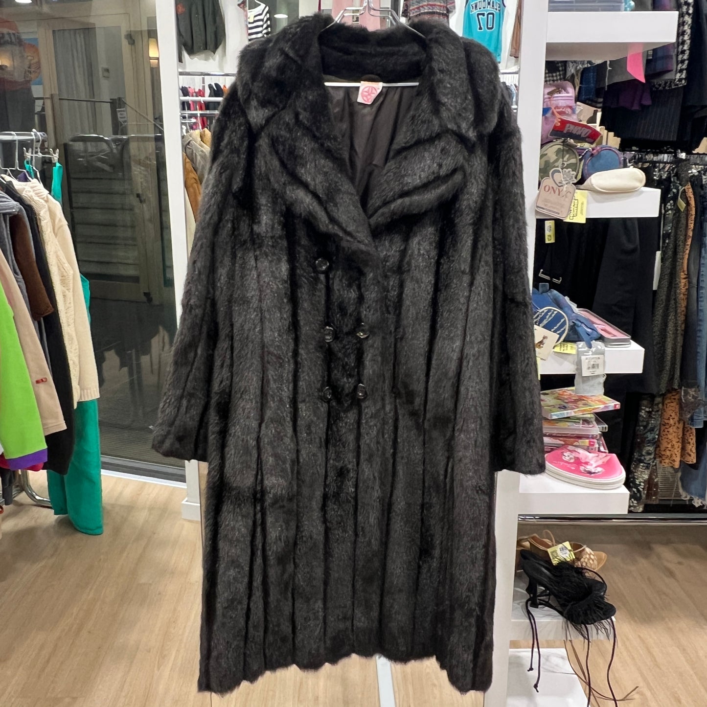 Dark brown fur coat on a hanger in a clothing store setting