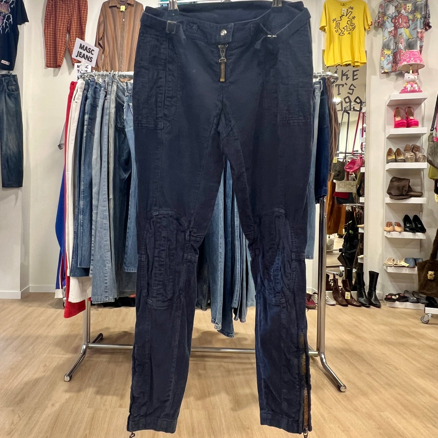 Navy blue pants displayed on a rack in a store setting with various clothing items in the background