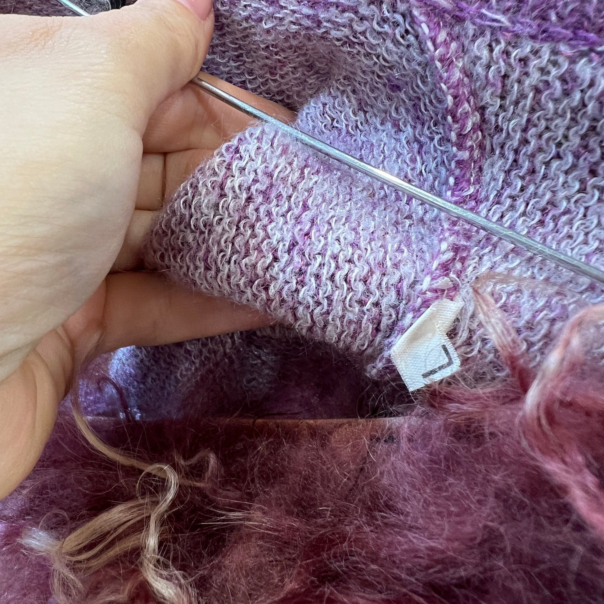 Close-up of knitting with purple yarn and a needle