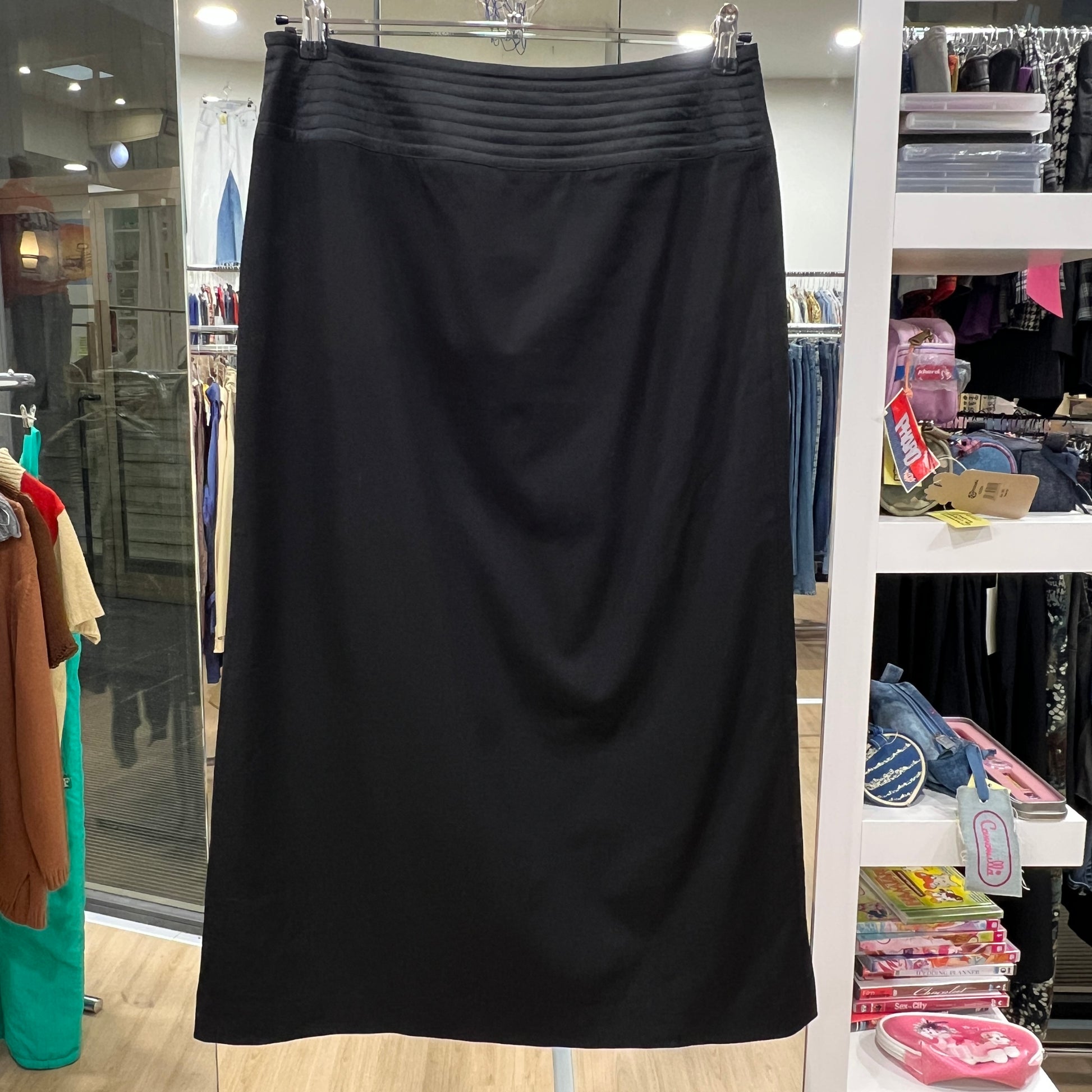 Black skirt hanging in a store with clothing racks and shelves in the background