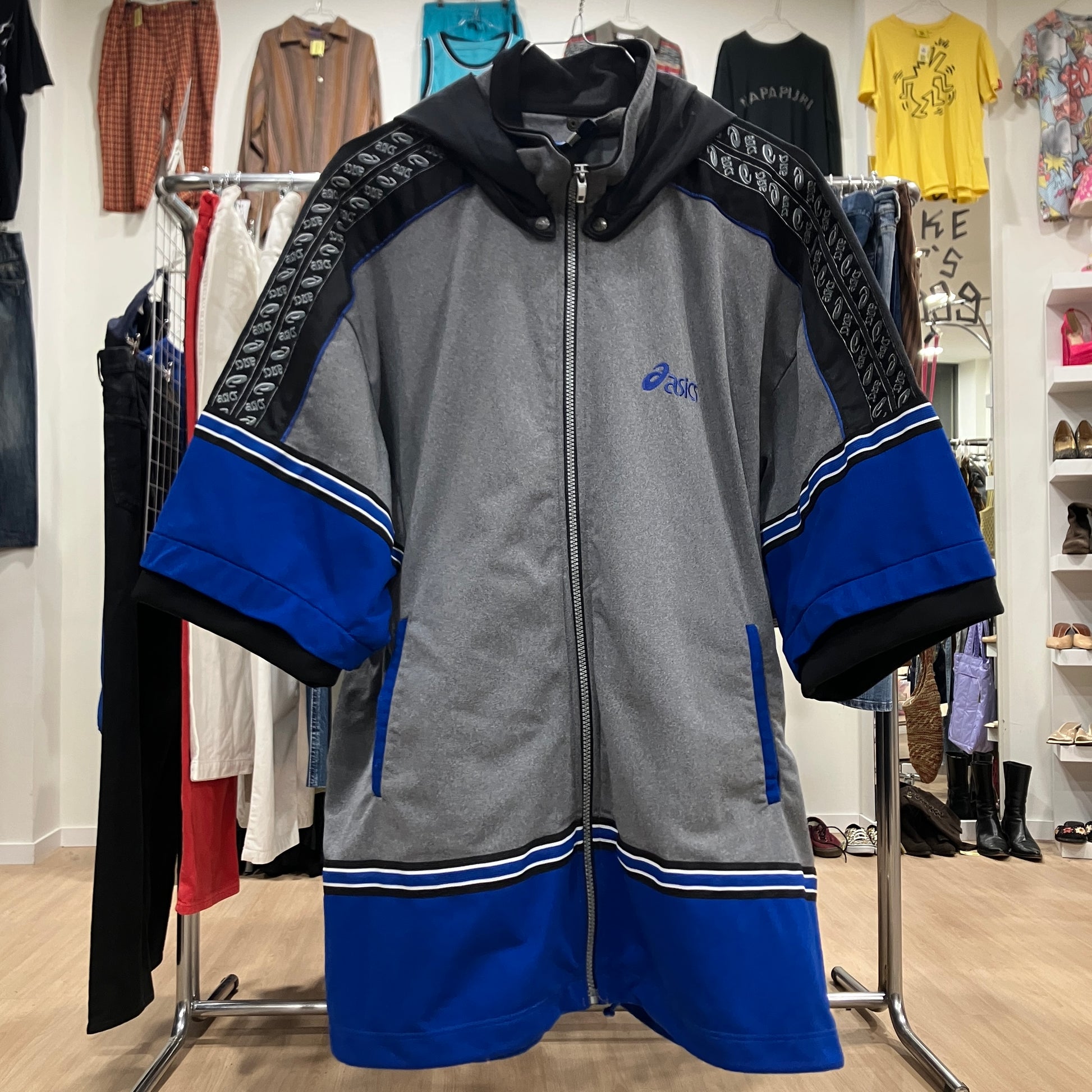 Gray and blue jacket with brand logo on a clothing rack in a store