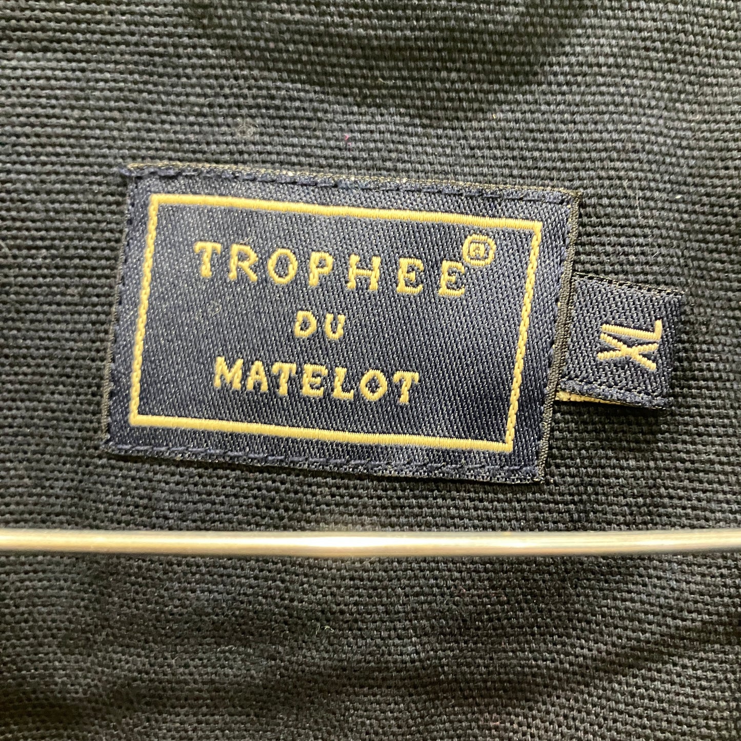 Label with 'Trophee du Matelot' on a dark fabric background