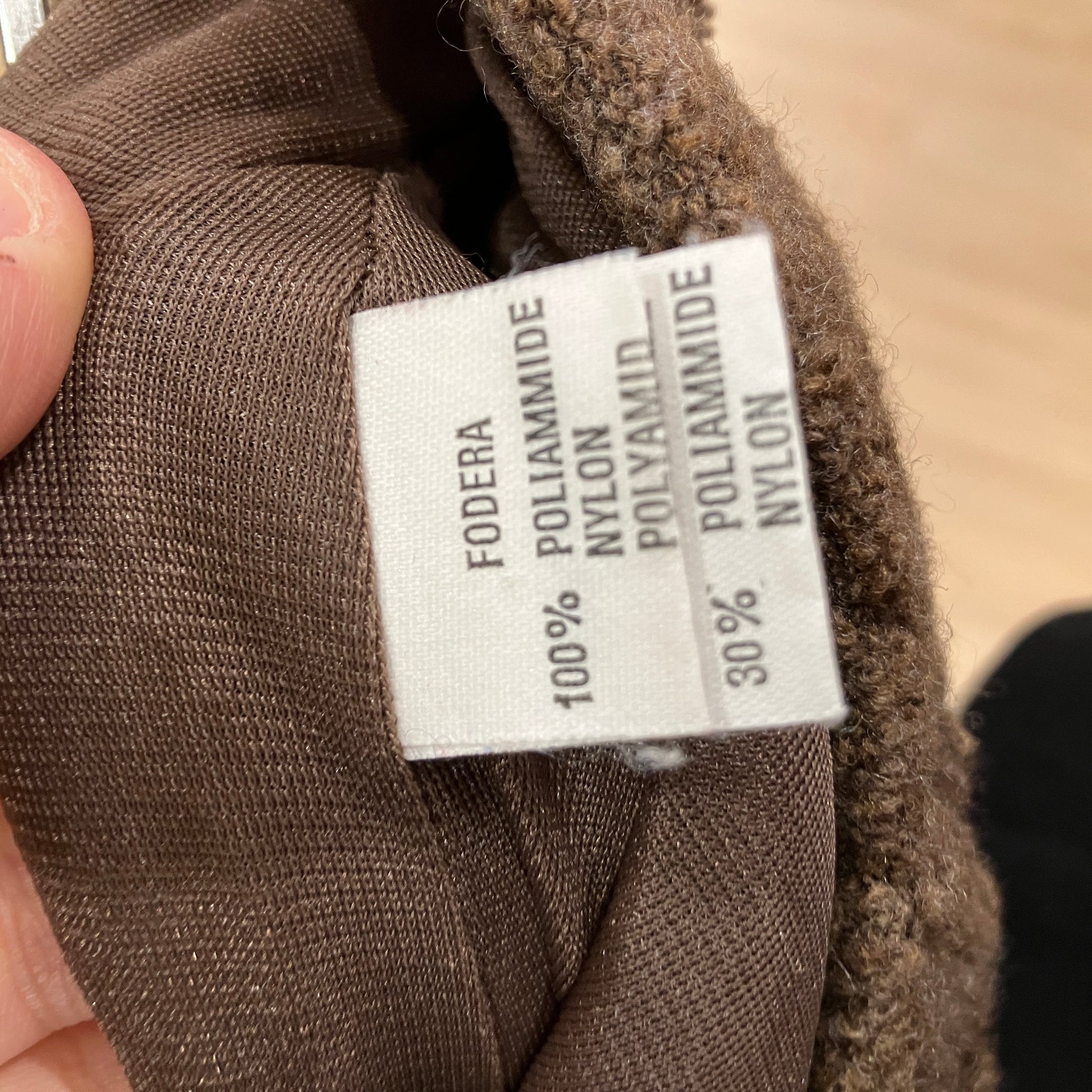 Close-up of a fabric label on brown material with text 'FODERA POLIAMMIDE NYLON'