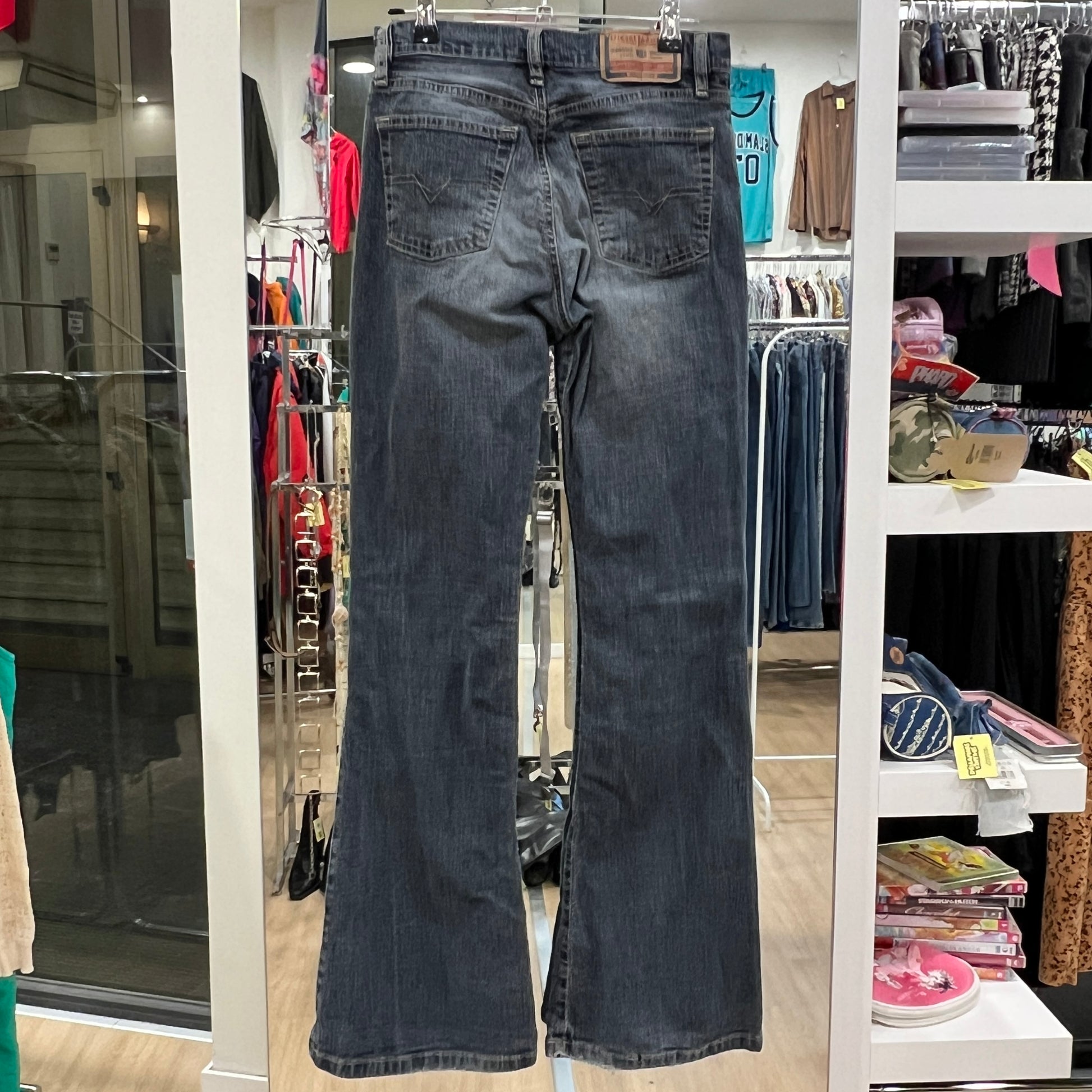Pair of blue jeans hanging in a store with various clothing items in the background