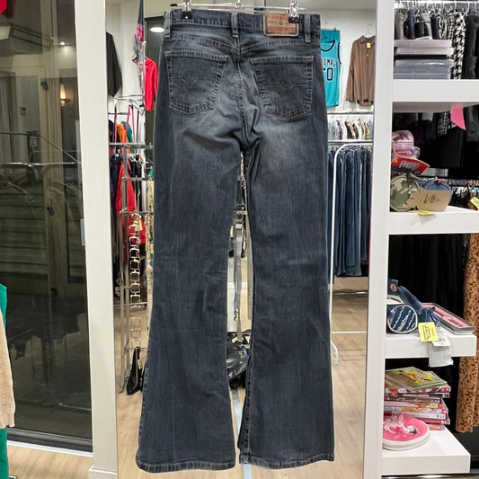 Pair of blue jeans hanging in a store with various clothing items in the background