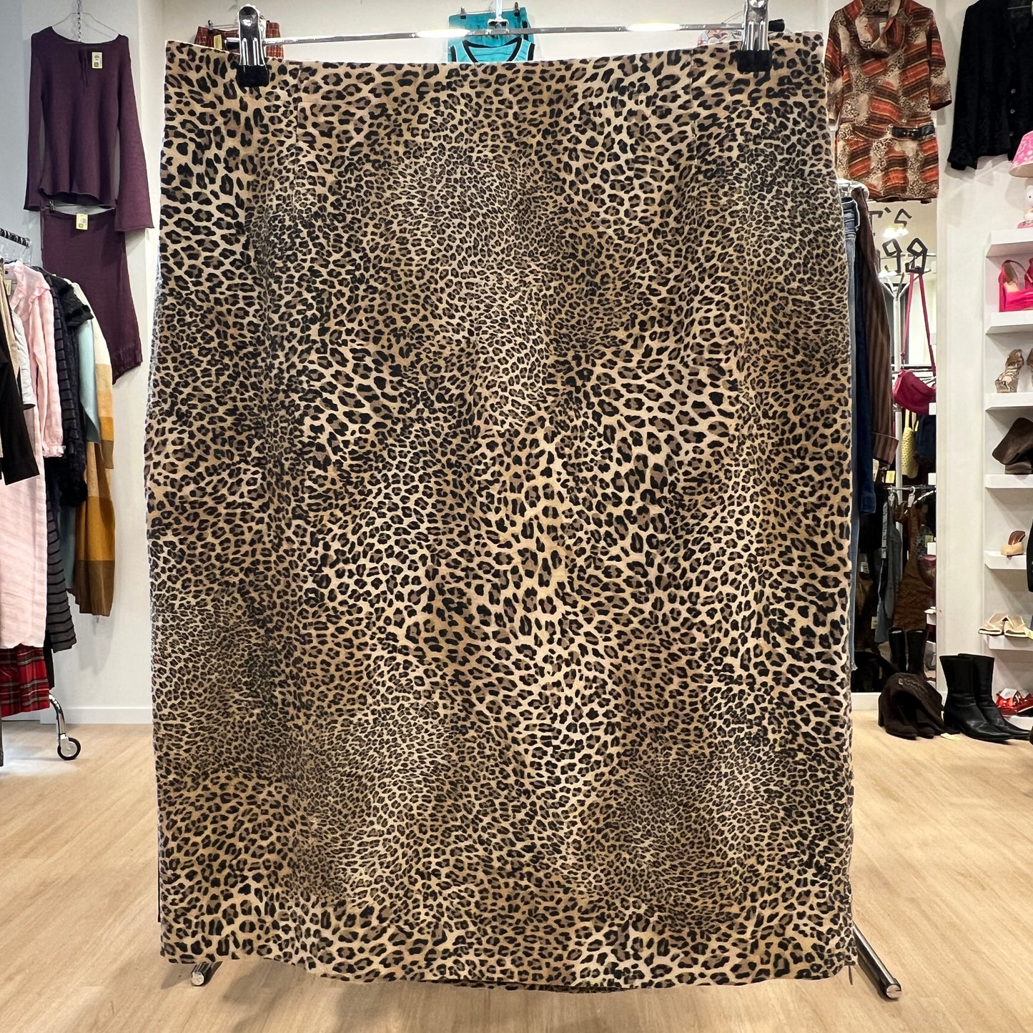 Leopard print fabric displayed in a store setting with clothing in the background