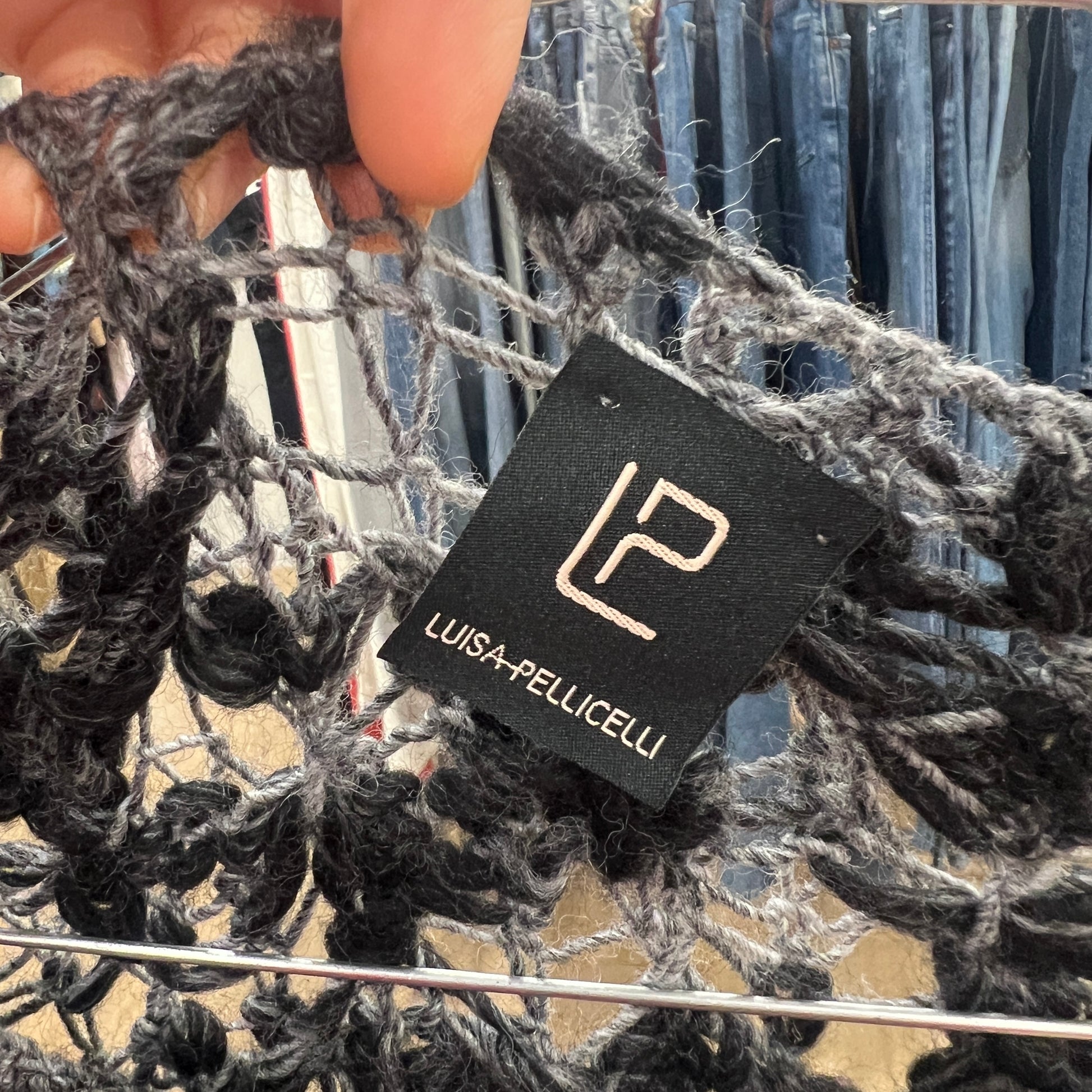 Close-up of a textured fabric with a Luisa Pellicelli tag in the foreground