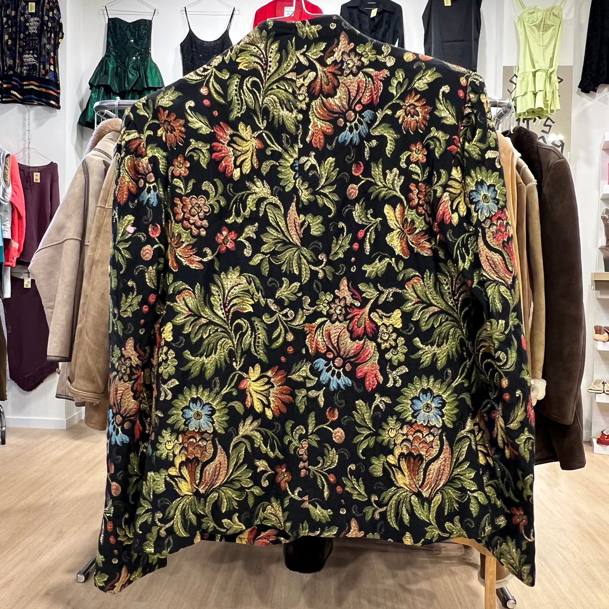 Floral patterned blazer on a rack in a store setting with other clothing items