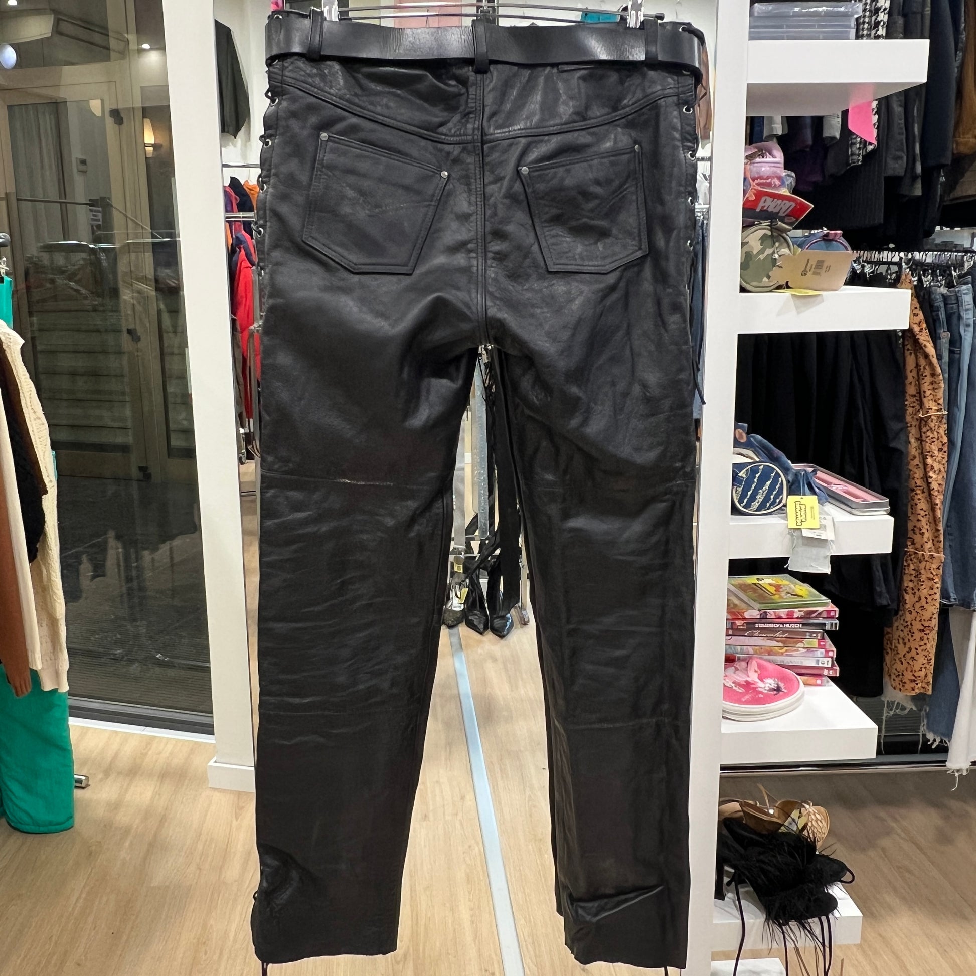 Black leather pants displayed on a rack in a store setting